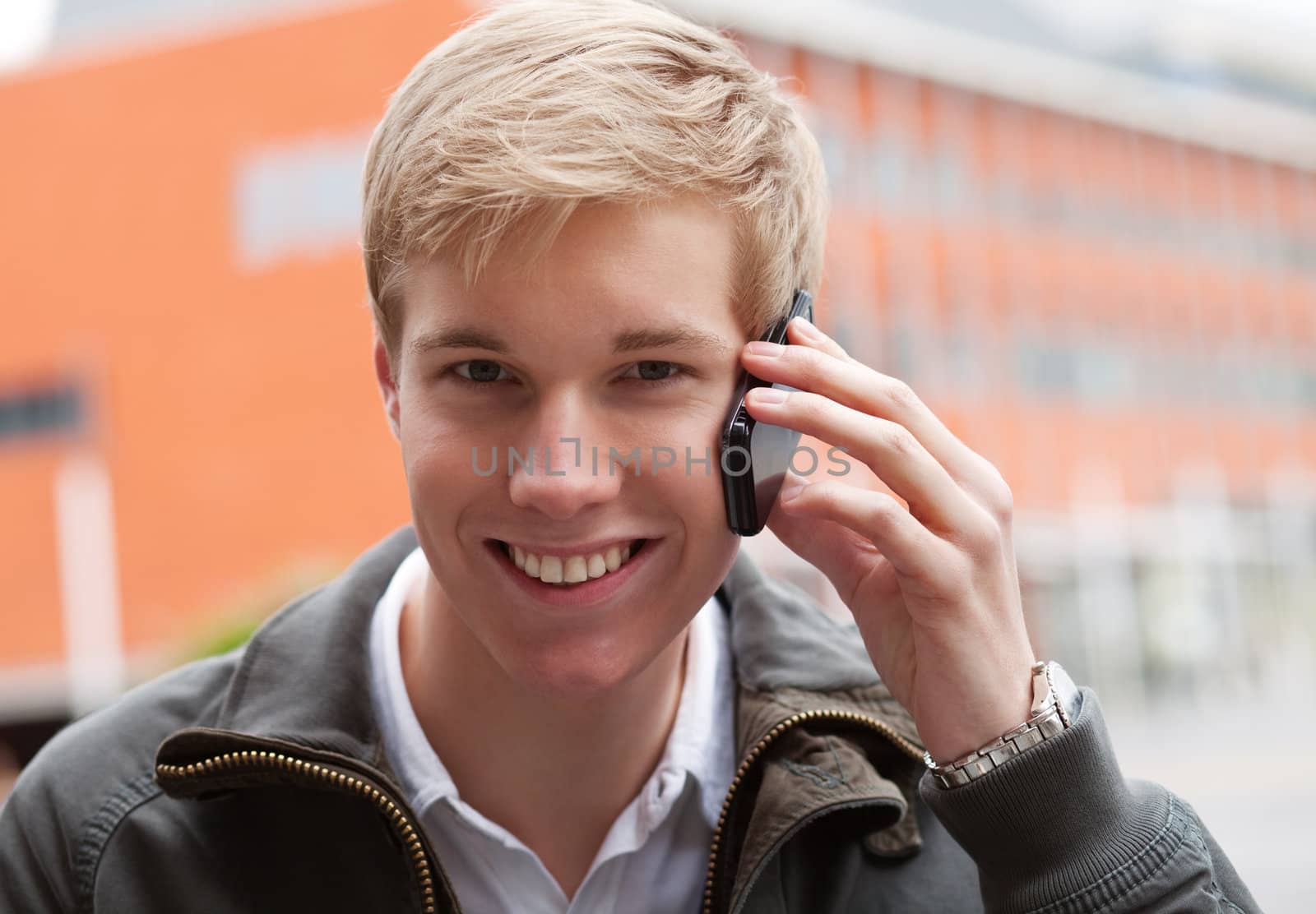 Young blond handsome smiling guy with mobile phone