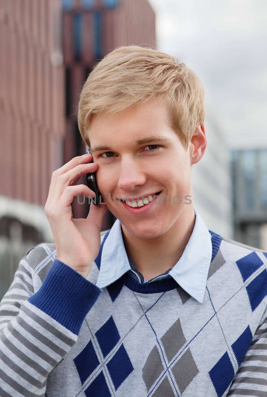 Young happy handsome man speaking on cellphone outdoors