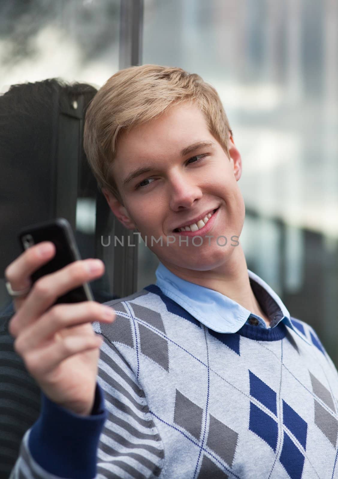 Happy young man taking pictures with a cameraphone (or texting)