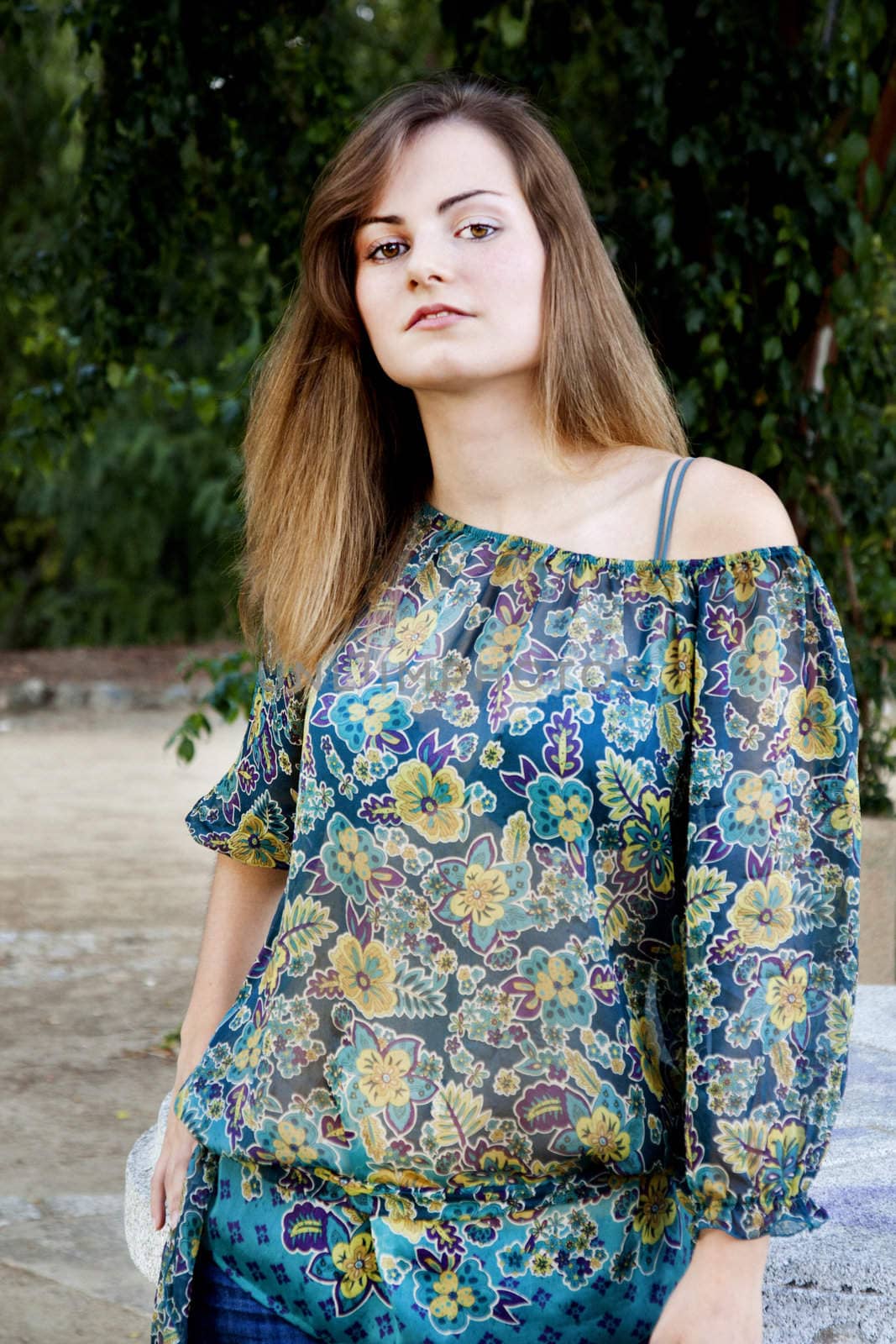 View of a beautiful girl on a floral dress on a park.