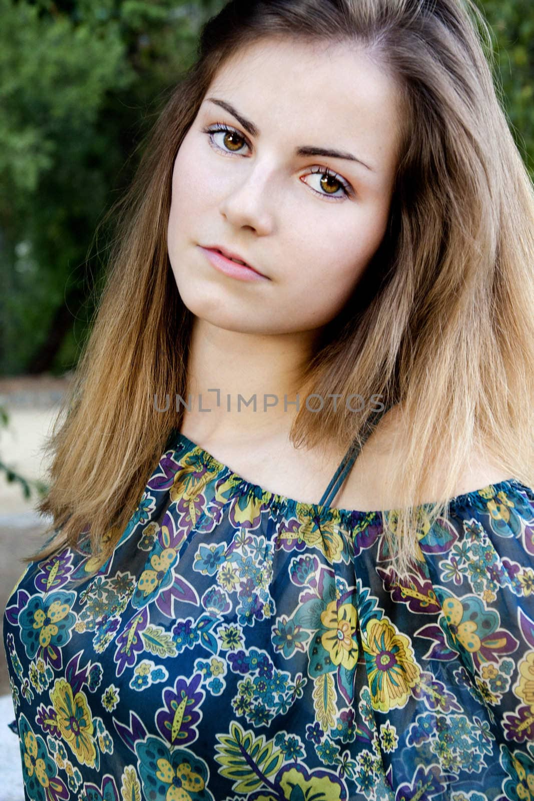 View of a beautiful girl on a floral dress on a park.