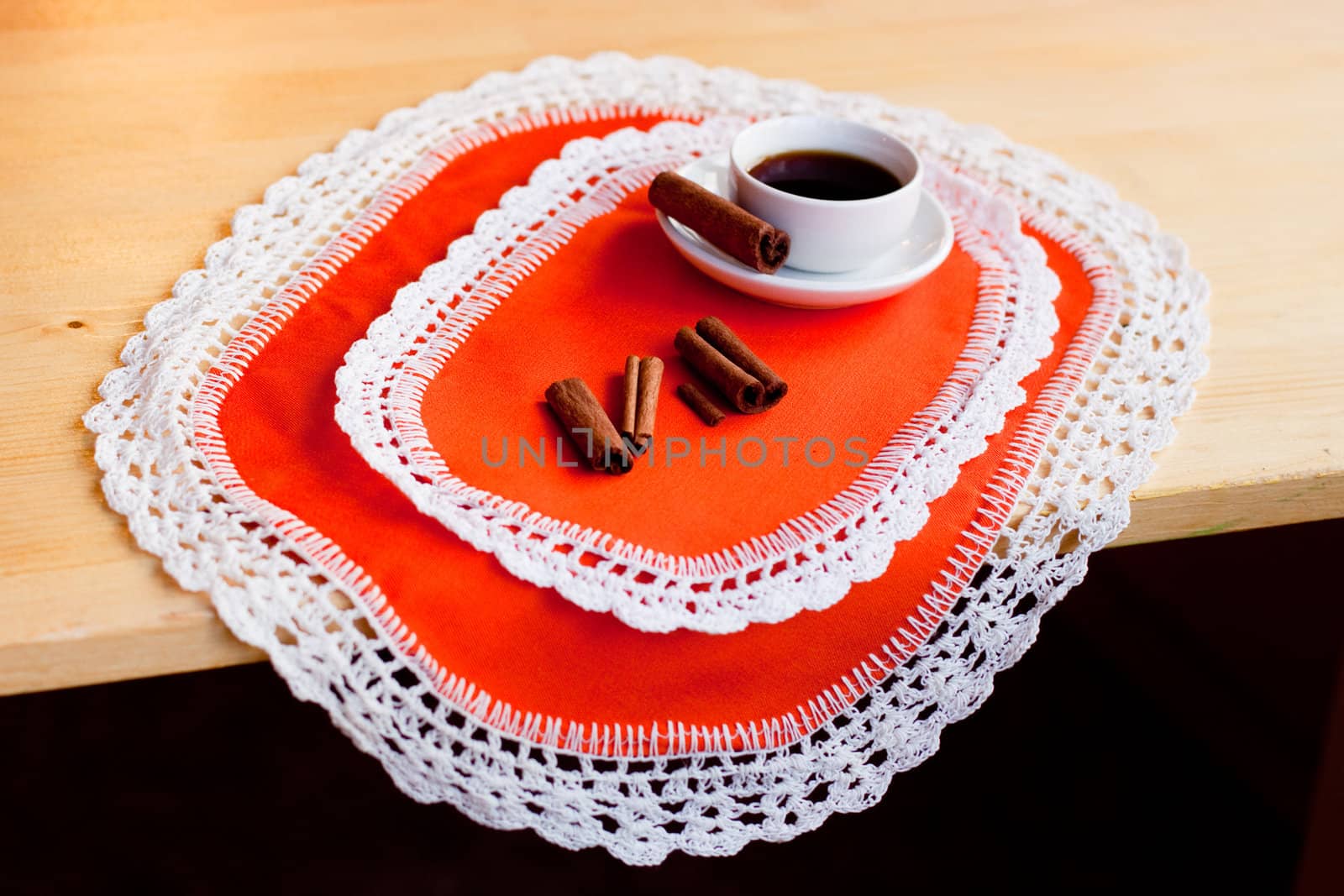 A coffee cup and several cinnamons on two orange napkins
