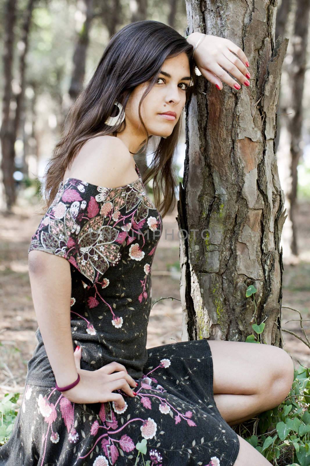 Beautiful girl with floral dress posing on a forest.