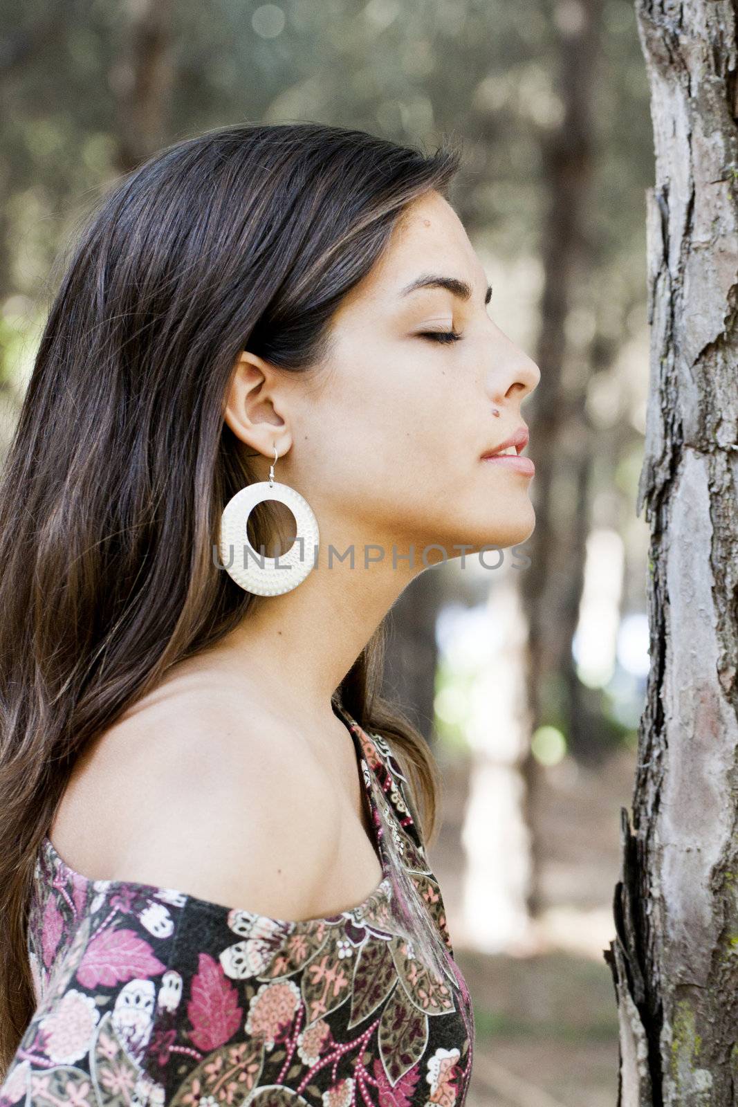 Beautiful girl with floral dress posing on a forest.