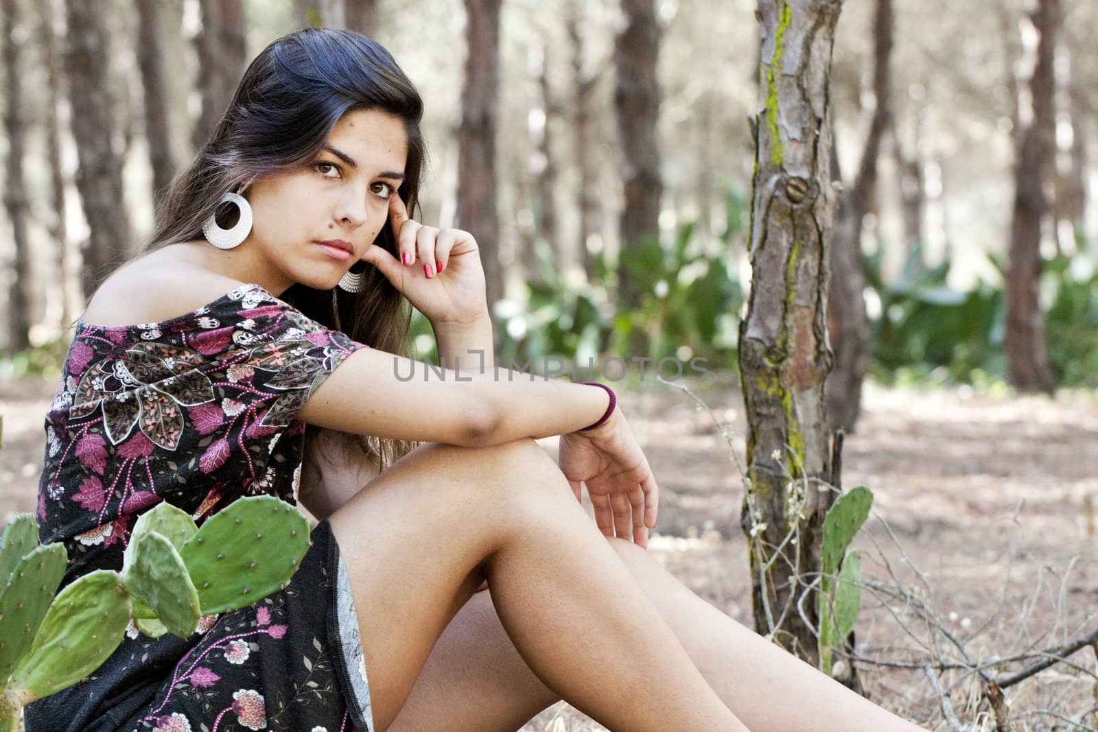 Beautiful girl with floral dress posing on a forest.