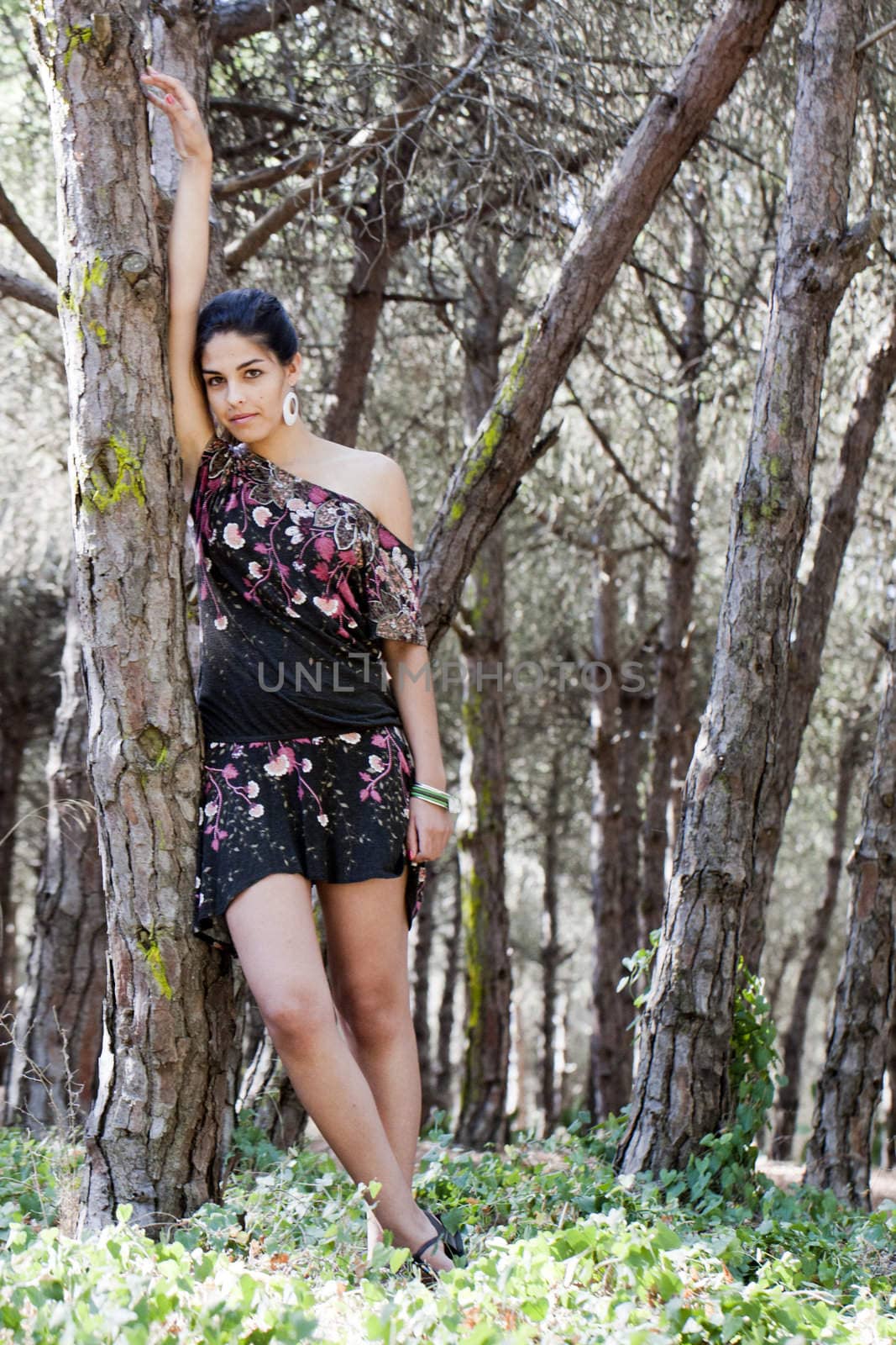 Beautiful girl with floral dress posing on a forest.