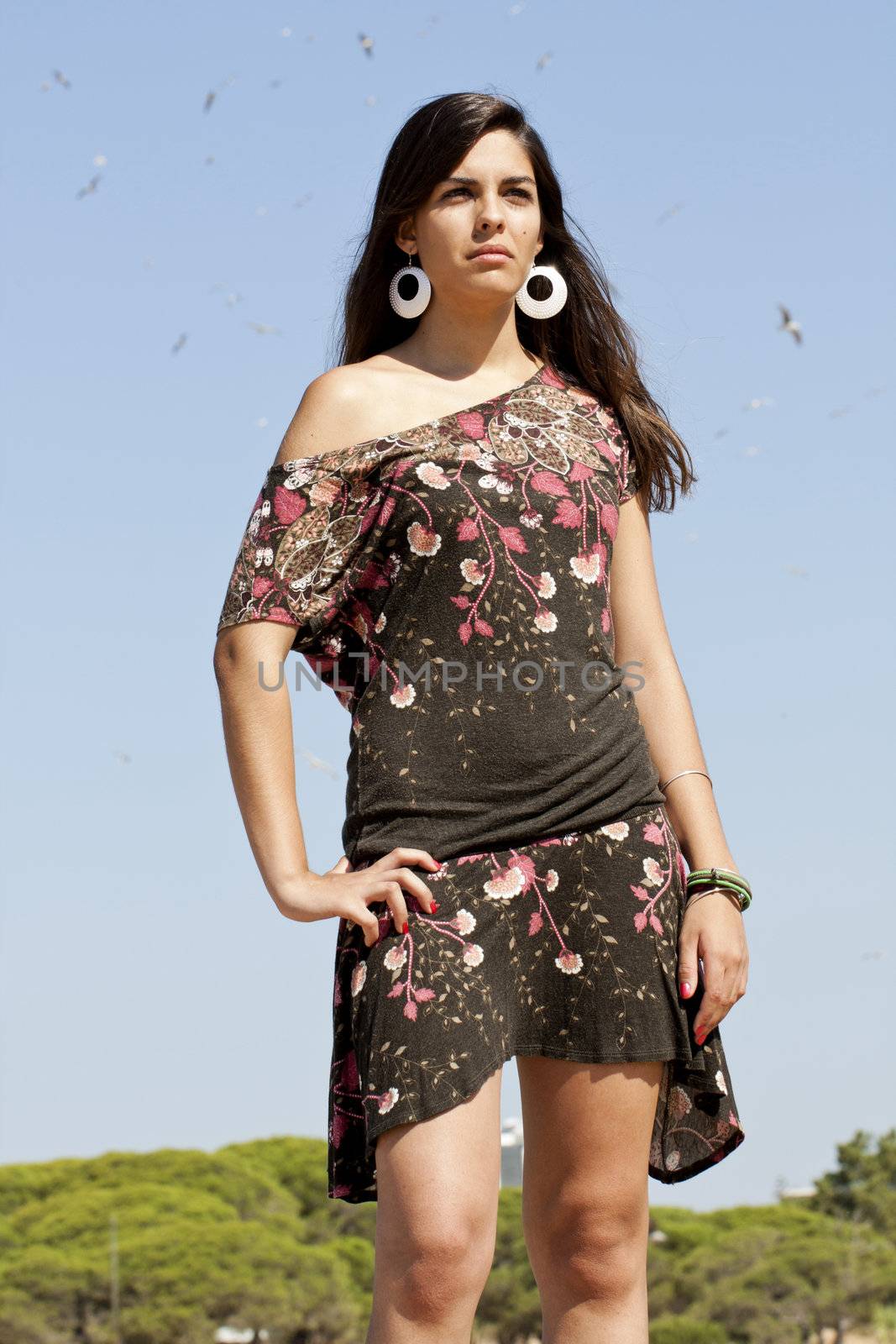Beautiful girl with floral dress posing on a forest with lots of birds.