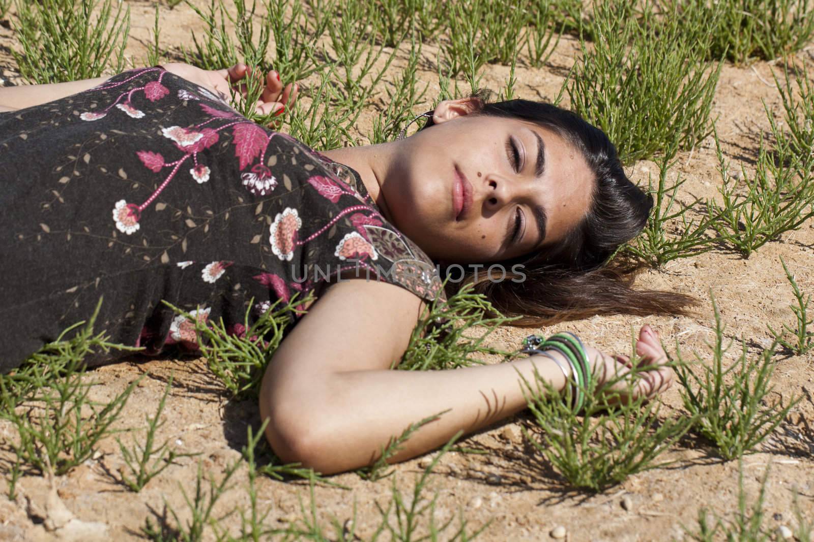 Beautiful girl with floral dress on the ground in a sunny day.