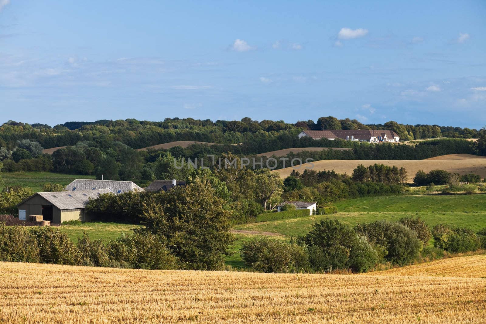 country landscape with farm buildings, fields, trees and hills