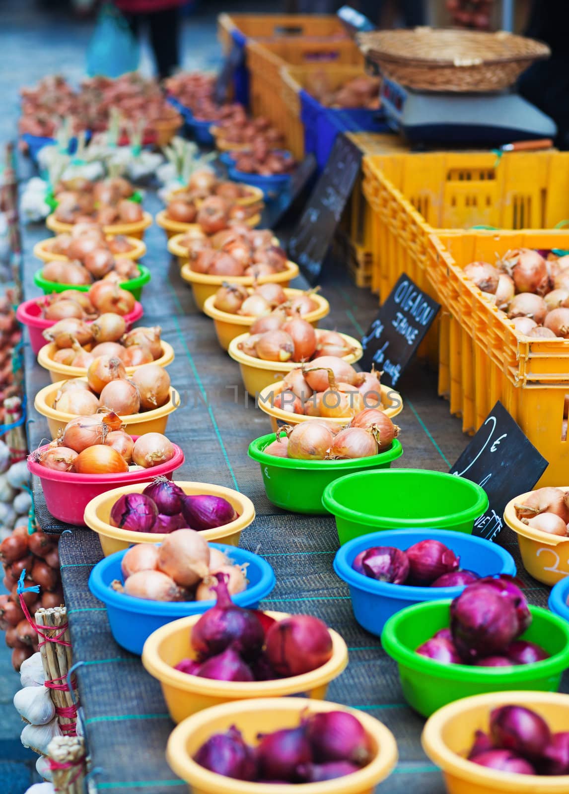 Farm market counter filled with colorful plastic bowls full of onions