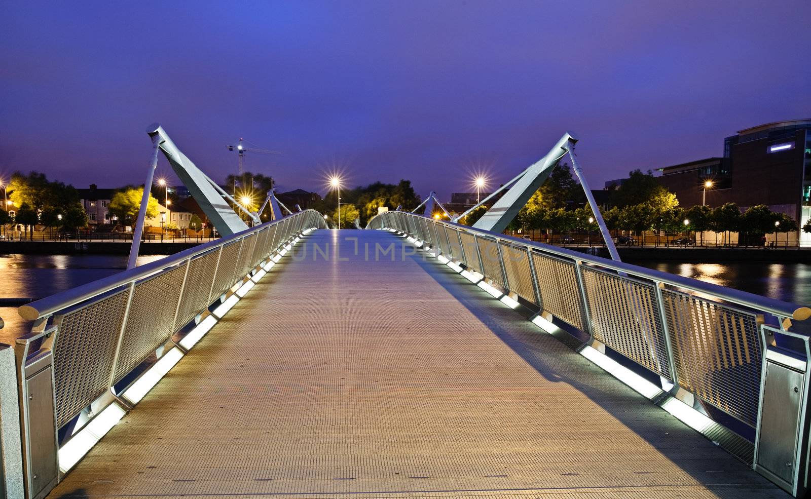 Illuminated pedestrian bridge across river Liffey in Dublin photographed in twilight