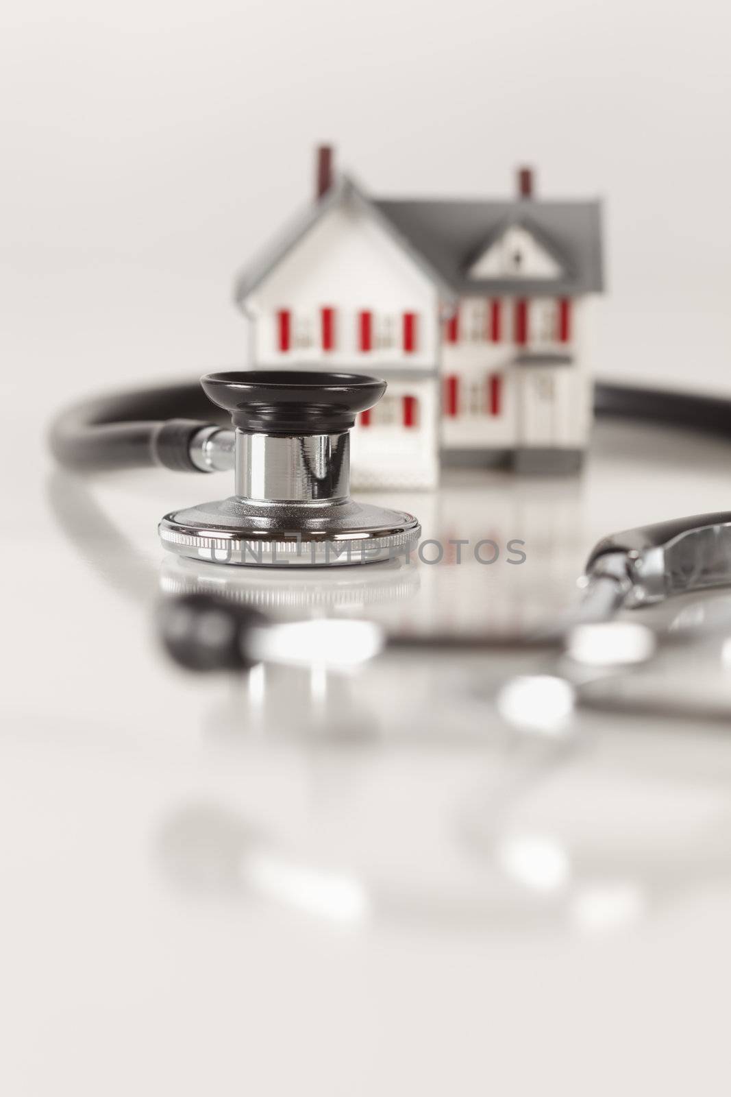 Stethoscope and Model House on Gradated Background with Selective Focus.