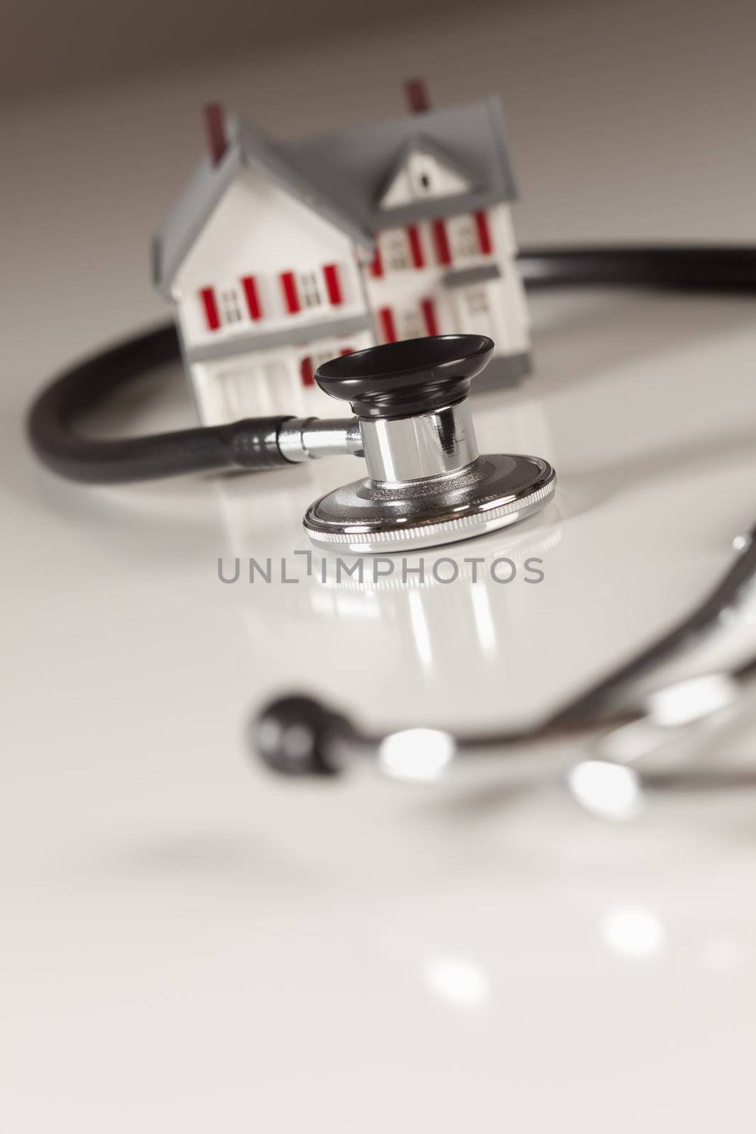 Stethoscope and Model House on Gradated Background with Selective Focus.