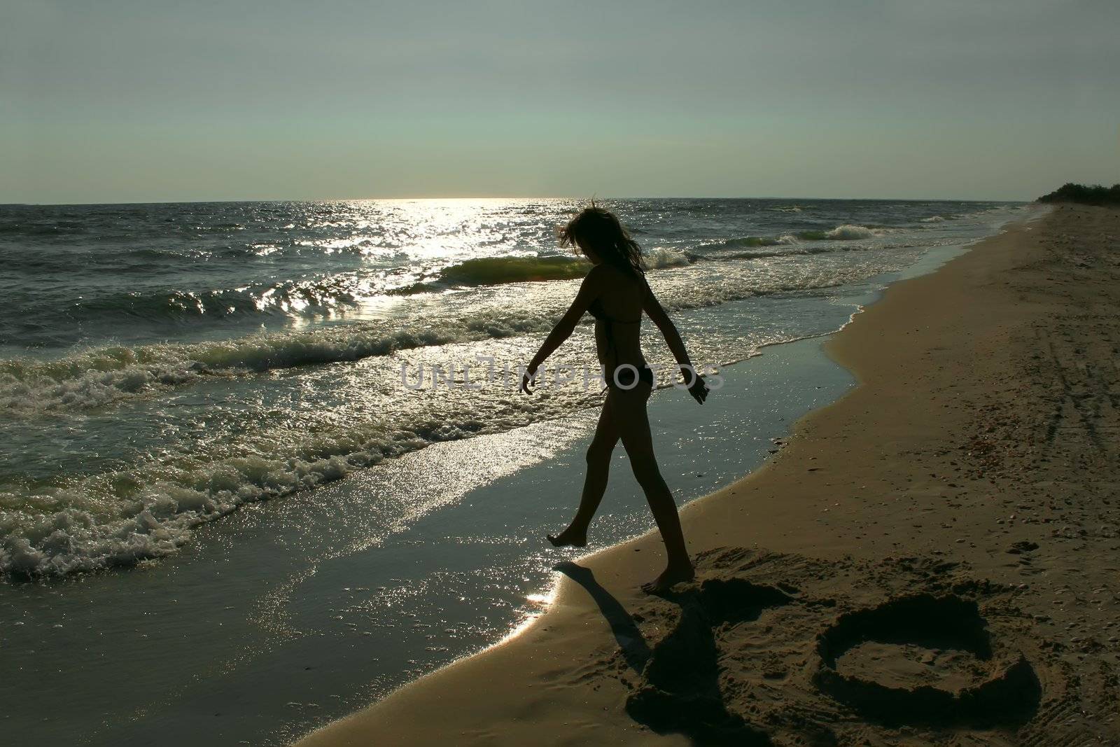 Teenage girl on an empty sea beach. Silhouette