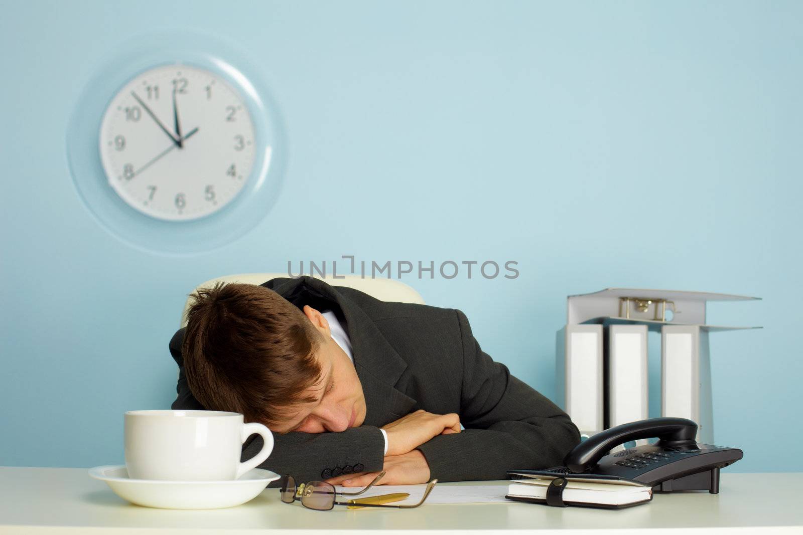 tired man sleeping on a table next to mug and phone
