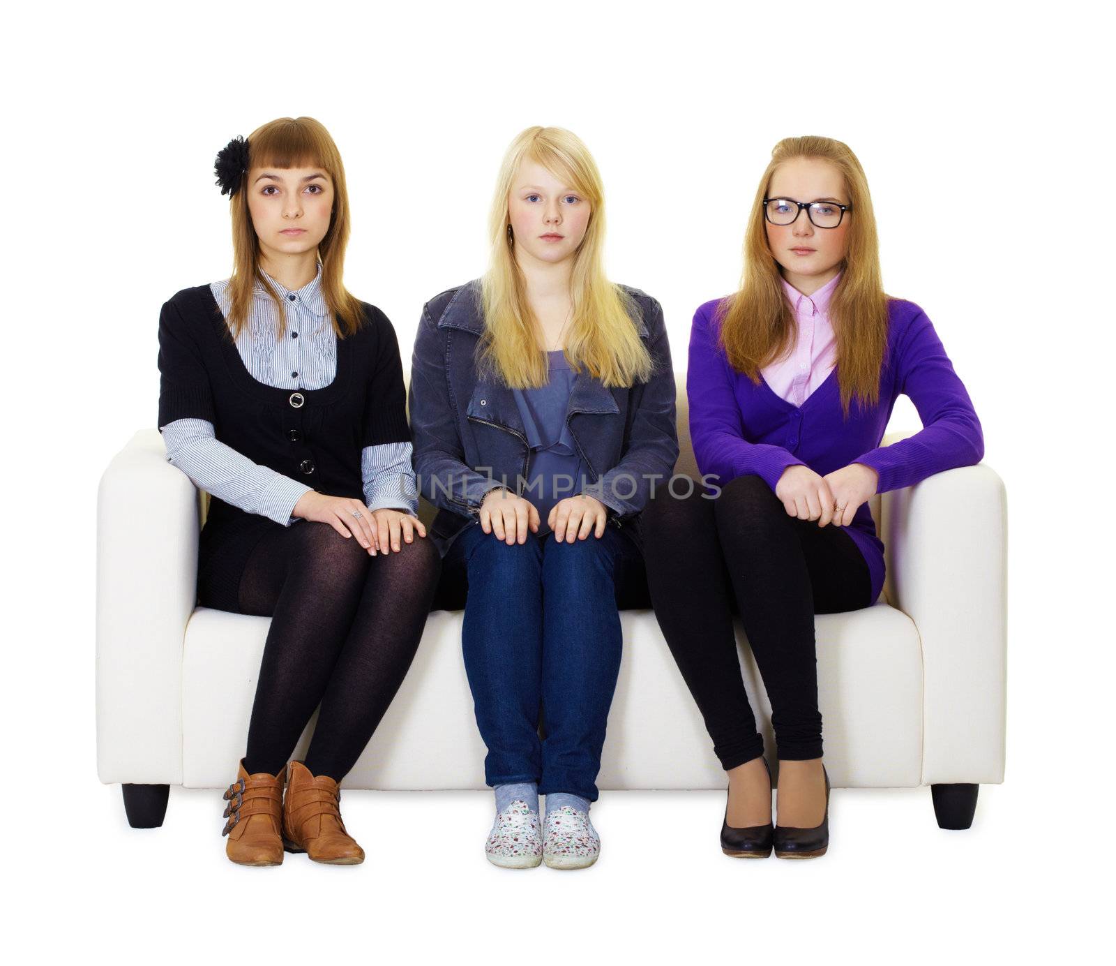 Three girls teenager sitting quietly on the couch and stares into the camera
