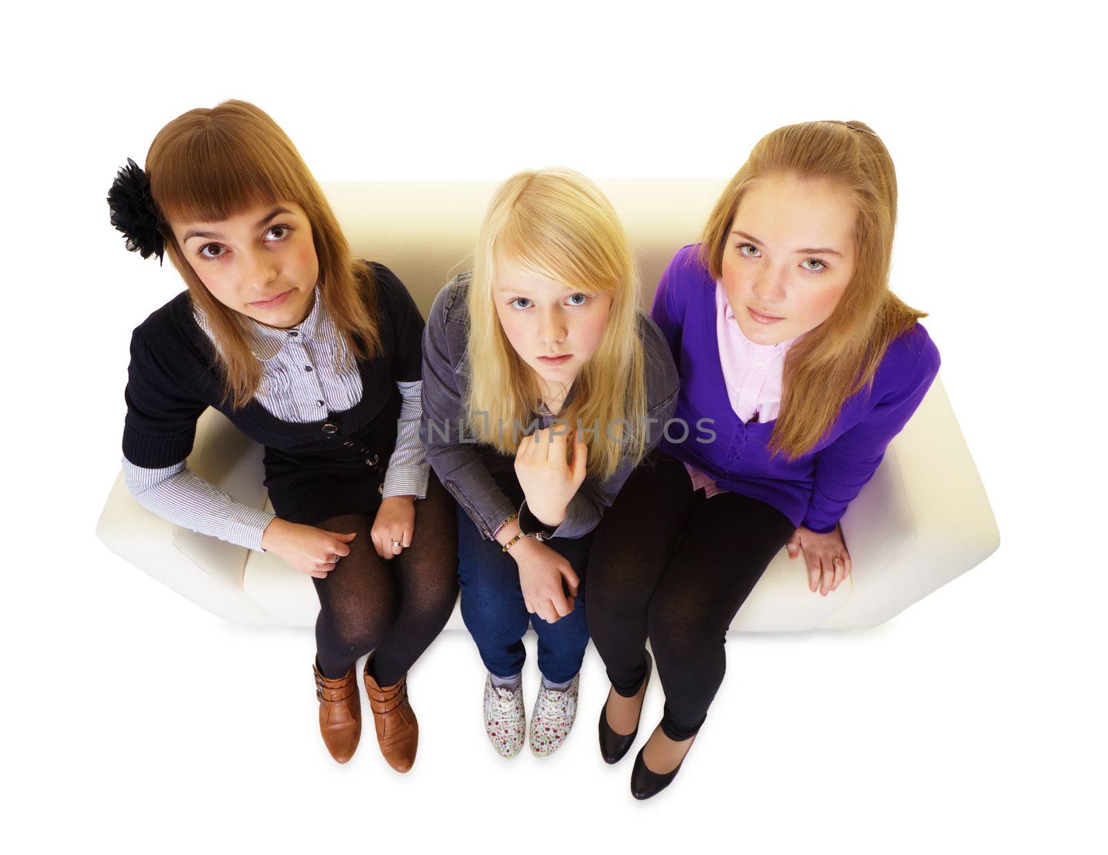 Three girlfriends on the couch teen on an isolated white background. Top view
