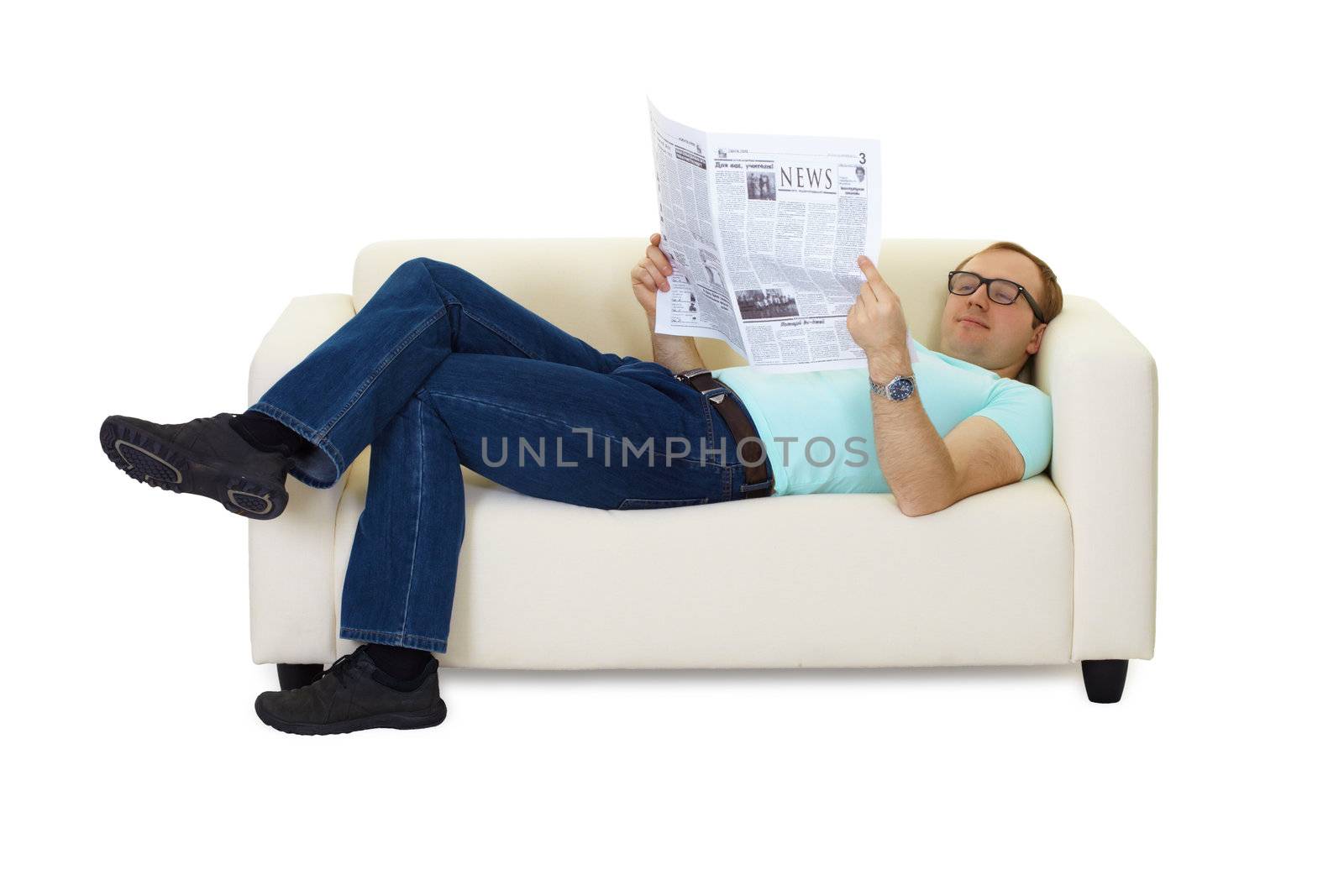man reading a newspaper lying on the couch at home
