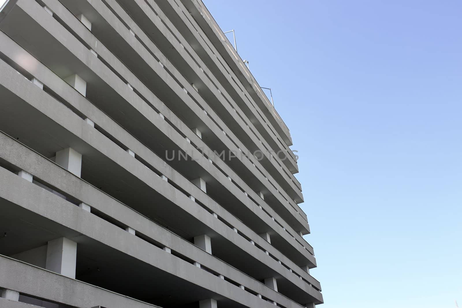 A multi-storey garage for cars in the background of blue sky. Fragment