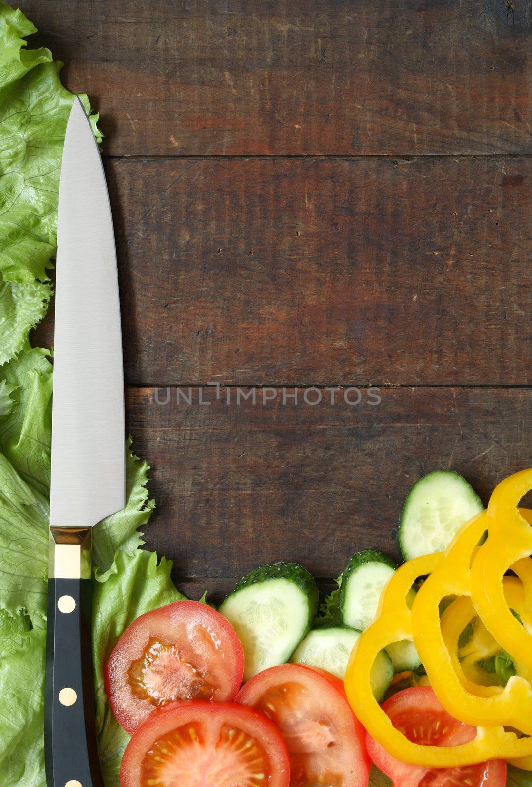 Kitchen knife and sliced vegetables lying on wooden surface with copy space