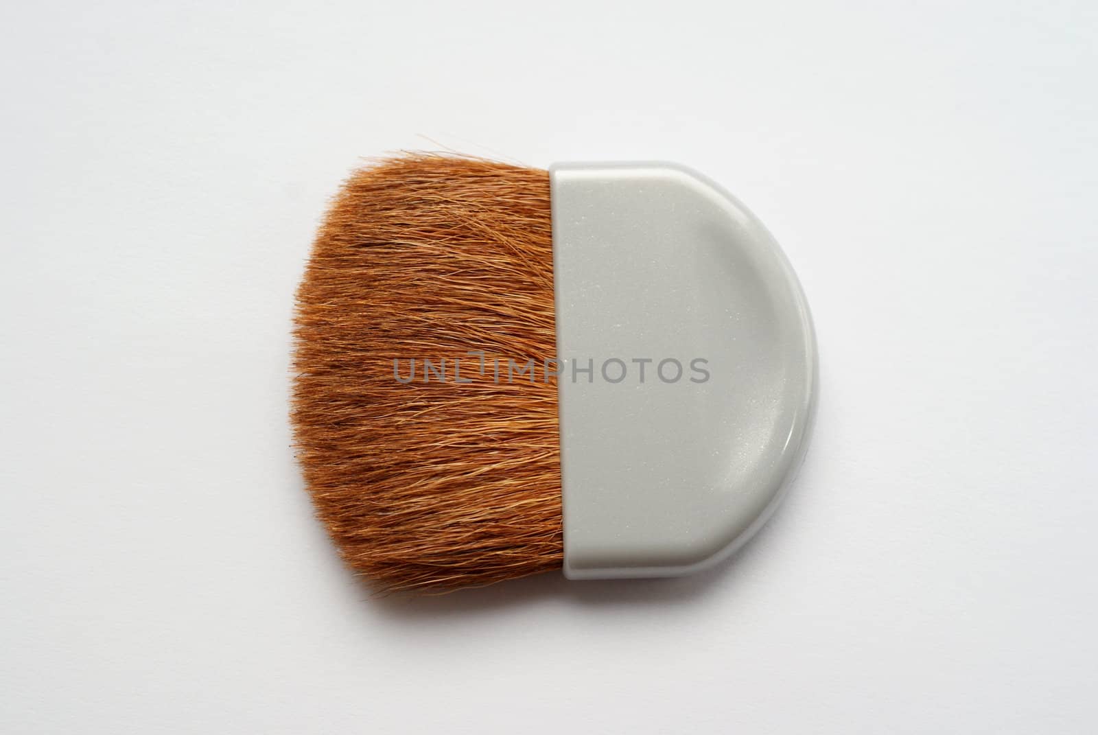 A small makeup brush for applying powder on white background. Shallow depth of field. 