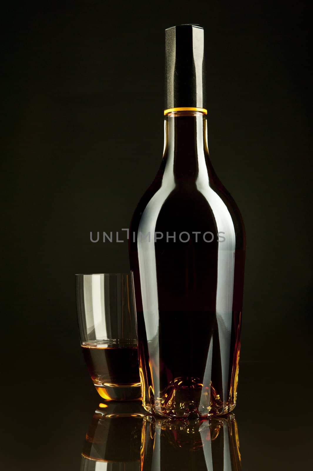 A bottle and a glass of cognac in a black background