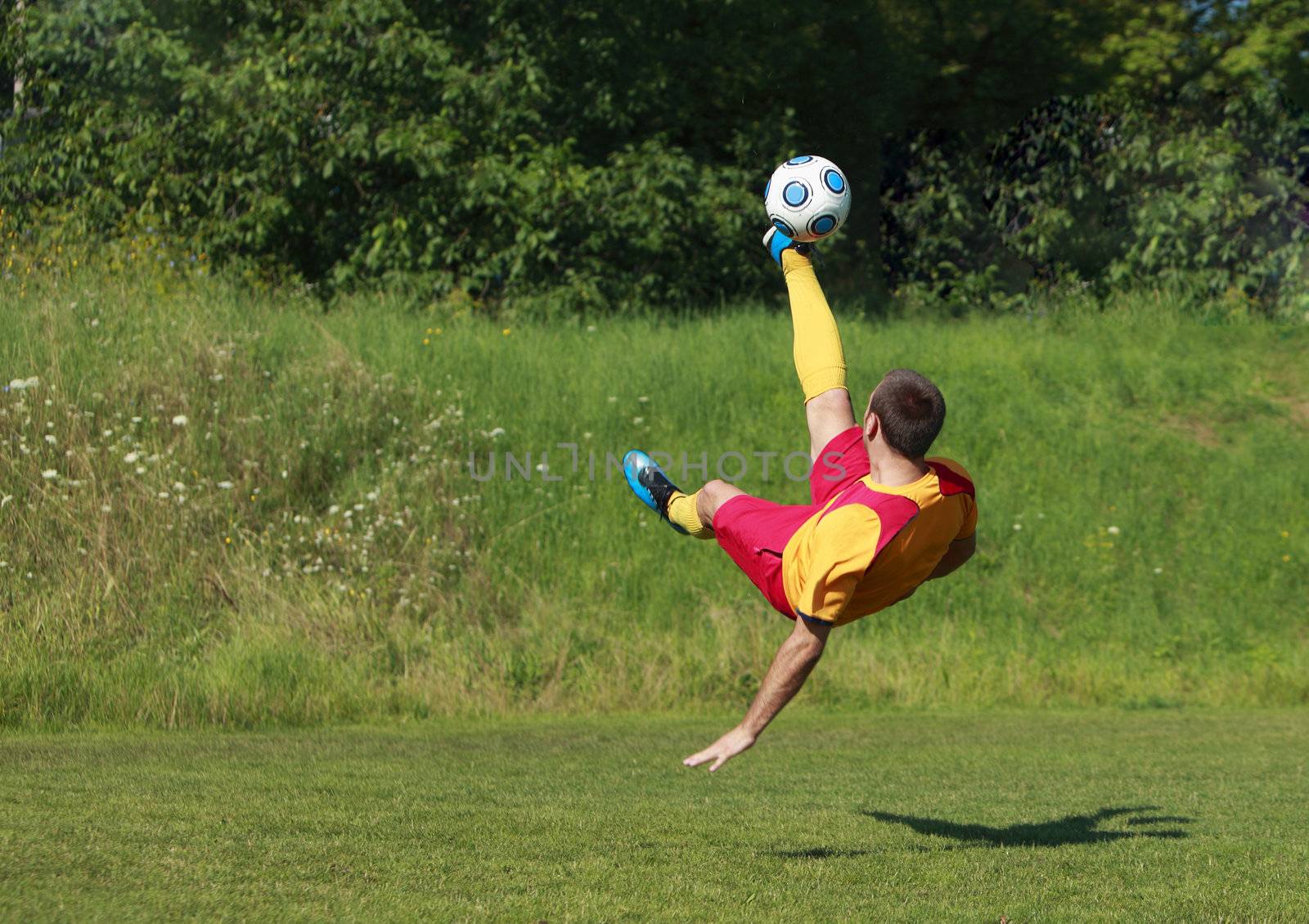 A soccer player kicking the ball in an acrobatic position.