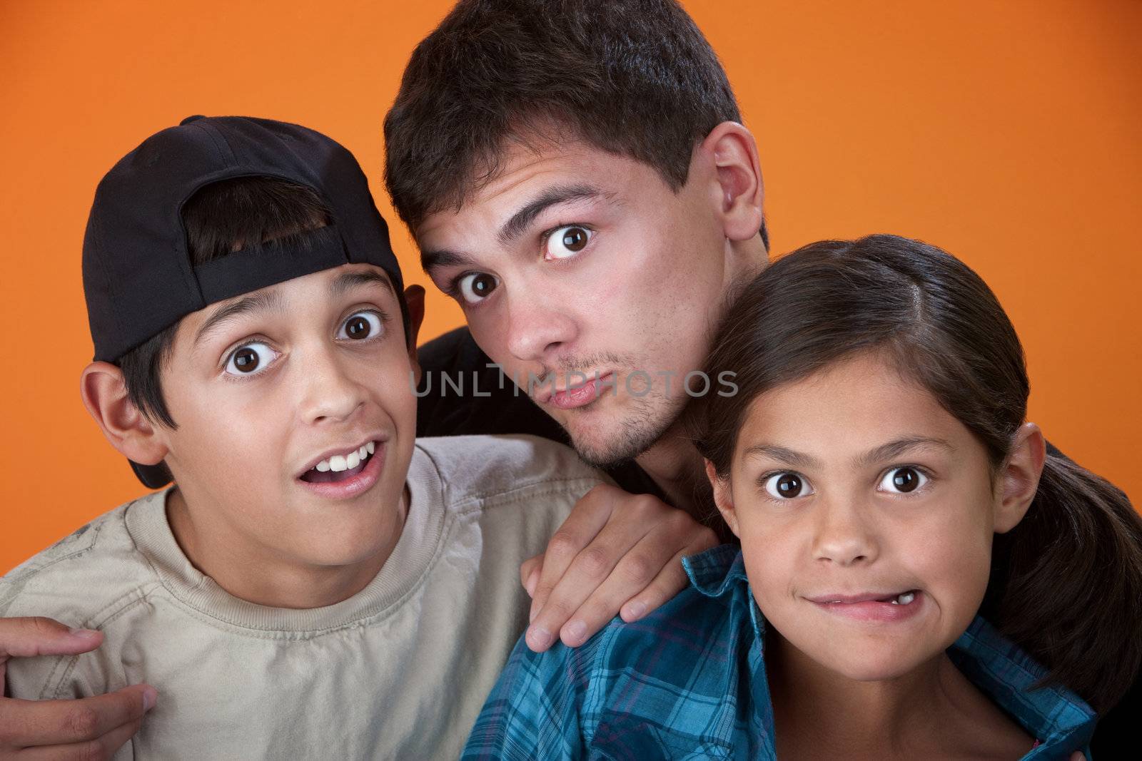 Elder brother with two younger siblings making faces