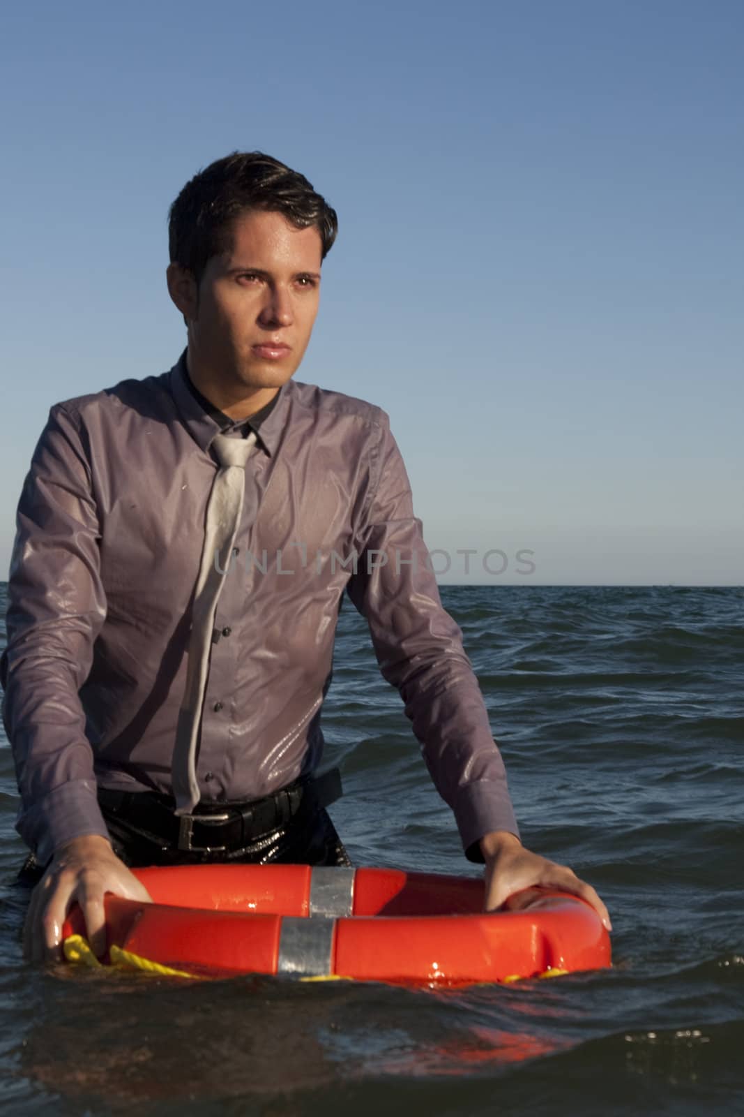 Business man holds a lifesaver buoy on the water.