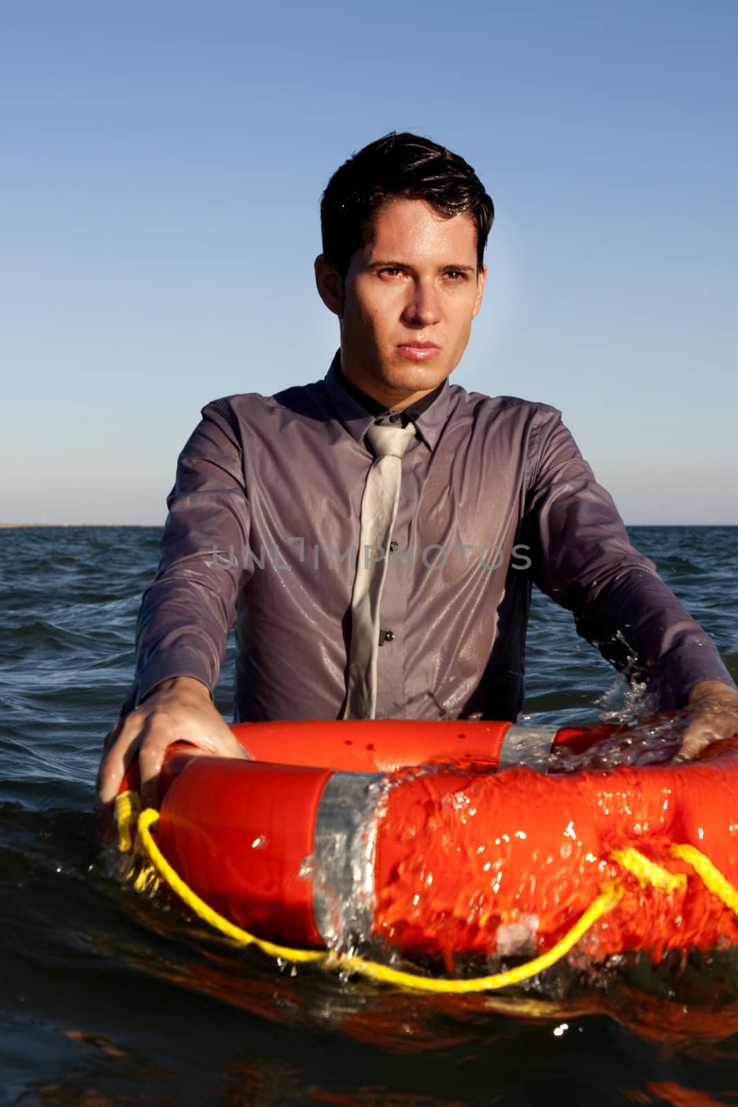 Business man holds a lifesaver buoy on the water.