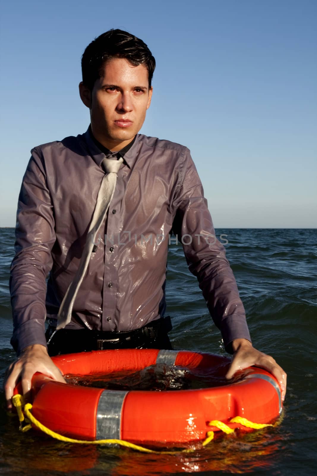 Business man holds a lifesaver buoy on the water.