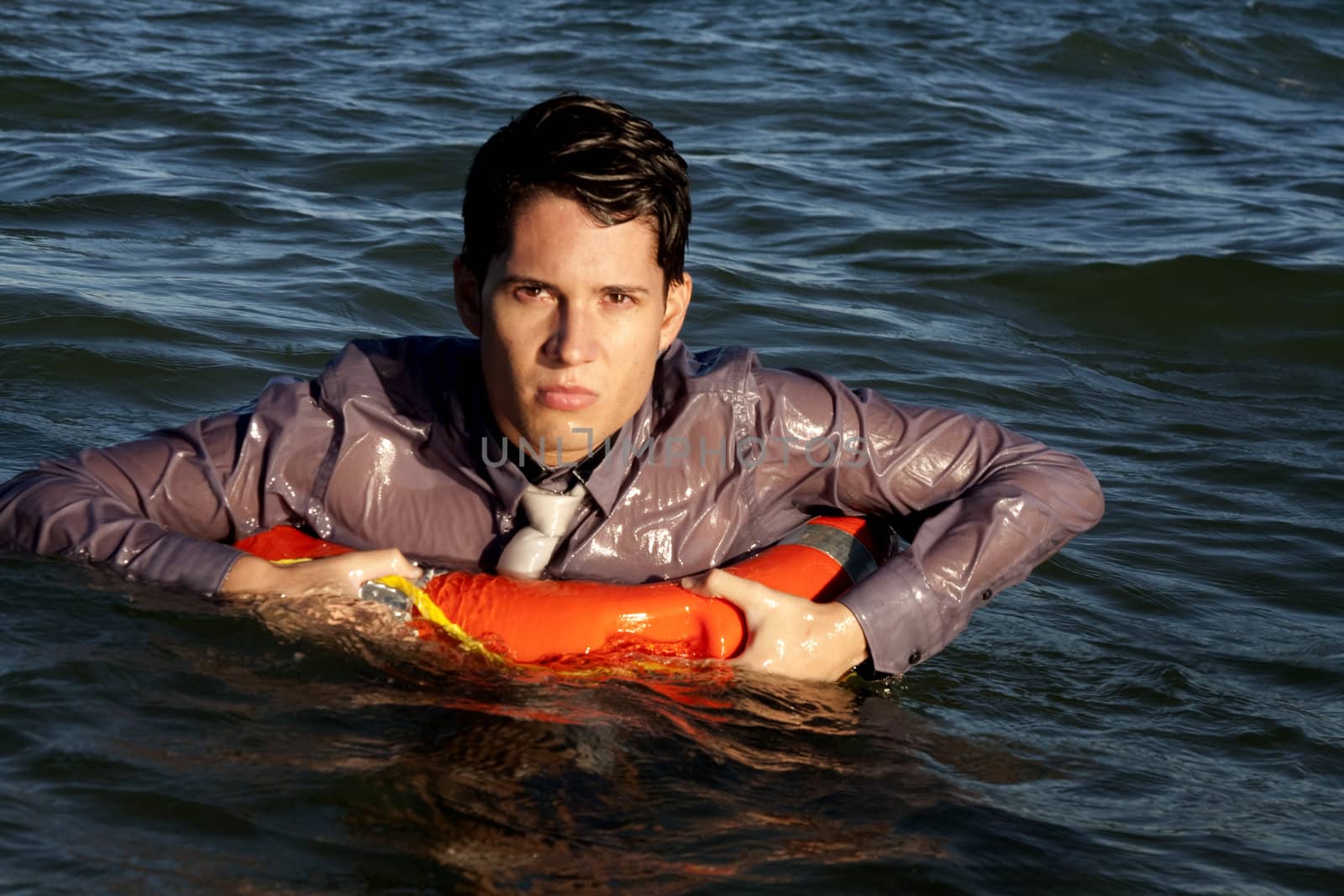 Business man holds a lifesaver buoy on the water.