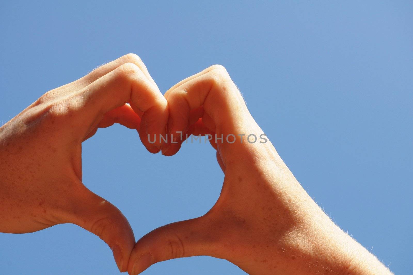 love concept with hand heart and blue sky copyspace