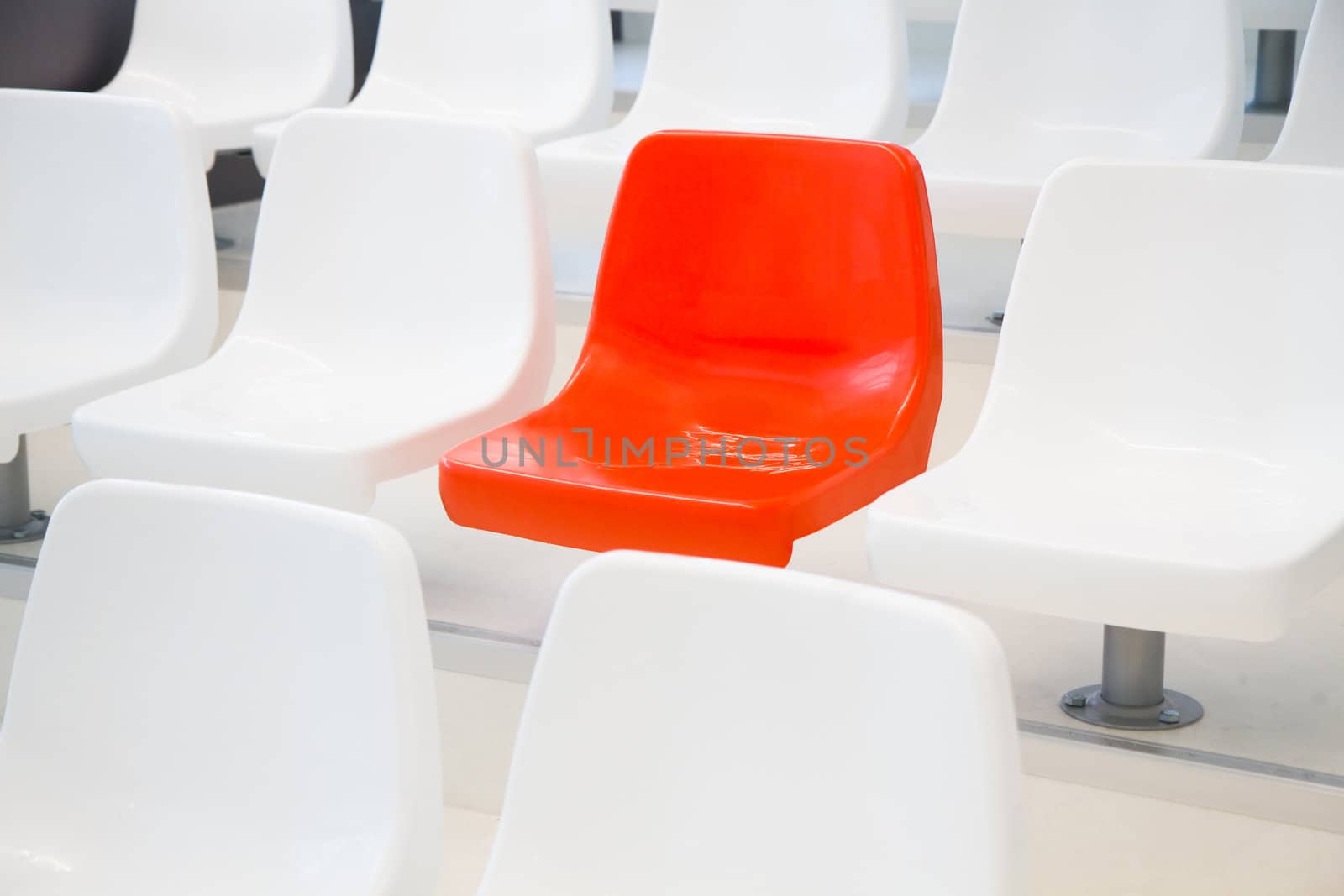 All the chairs are white, one is red - conceptual - horizontal image