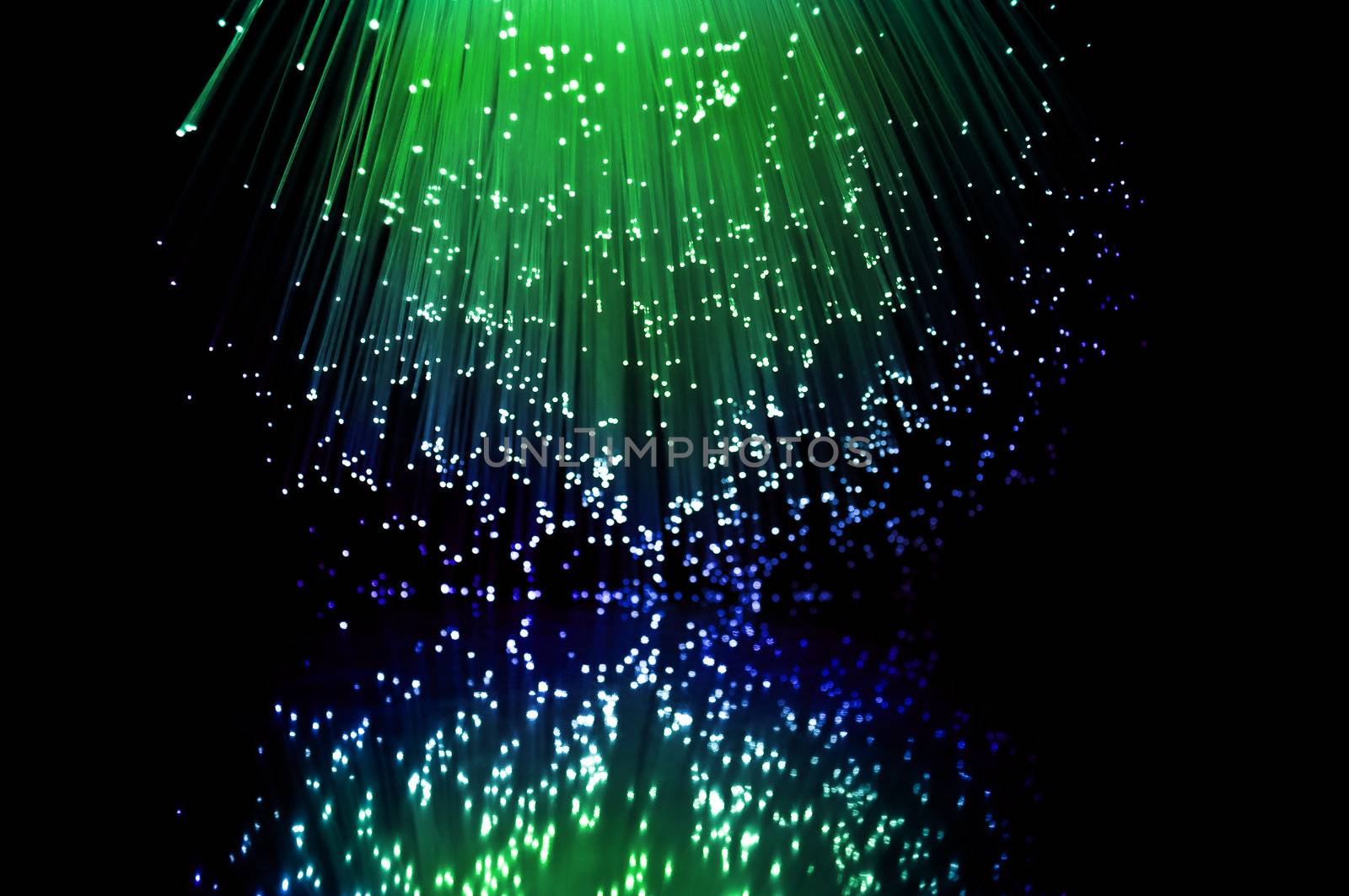 Green and blue fibre optic light strands reflecting in the foreground.