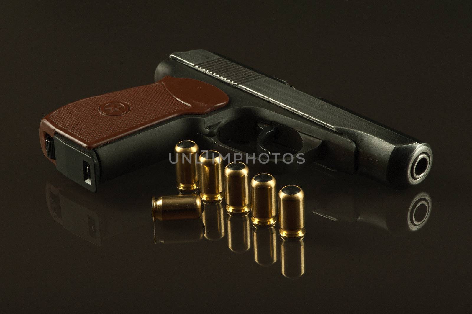 A gun and 7 bullets on a glass table over a dark background
