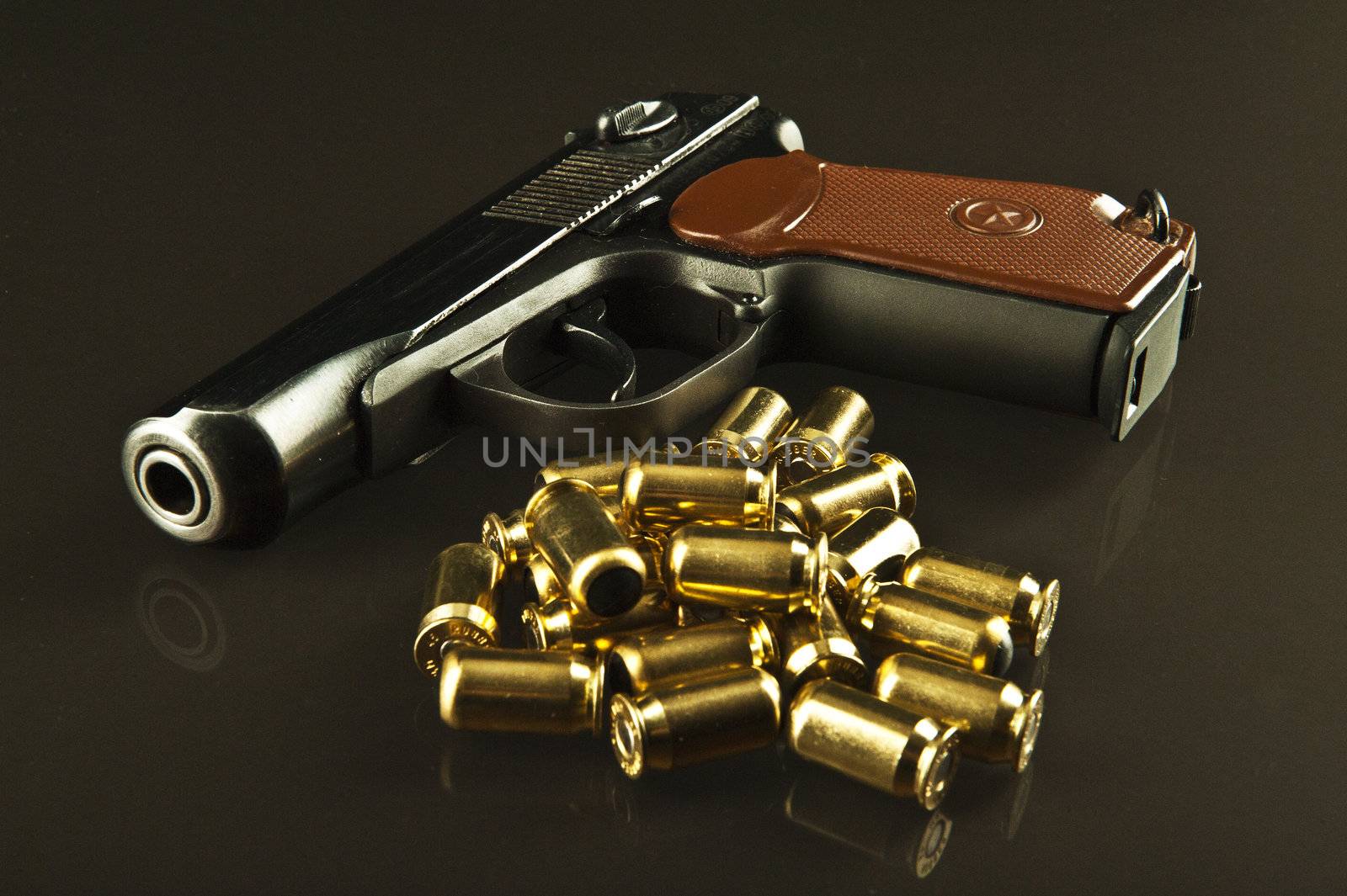 A gun and lots of bullets on a glass table over a dark background