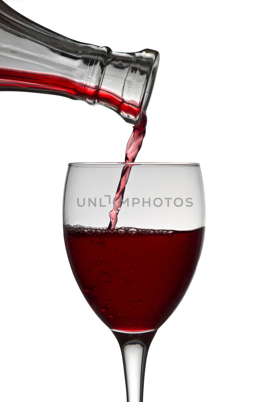 red wine pouring down from a wine decanter into a wine glass on white background