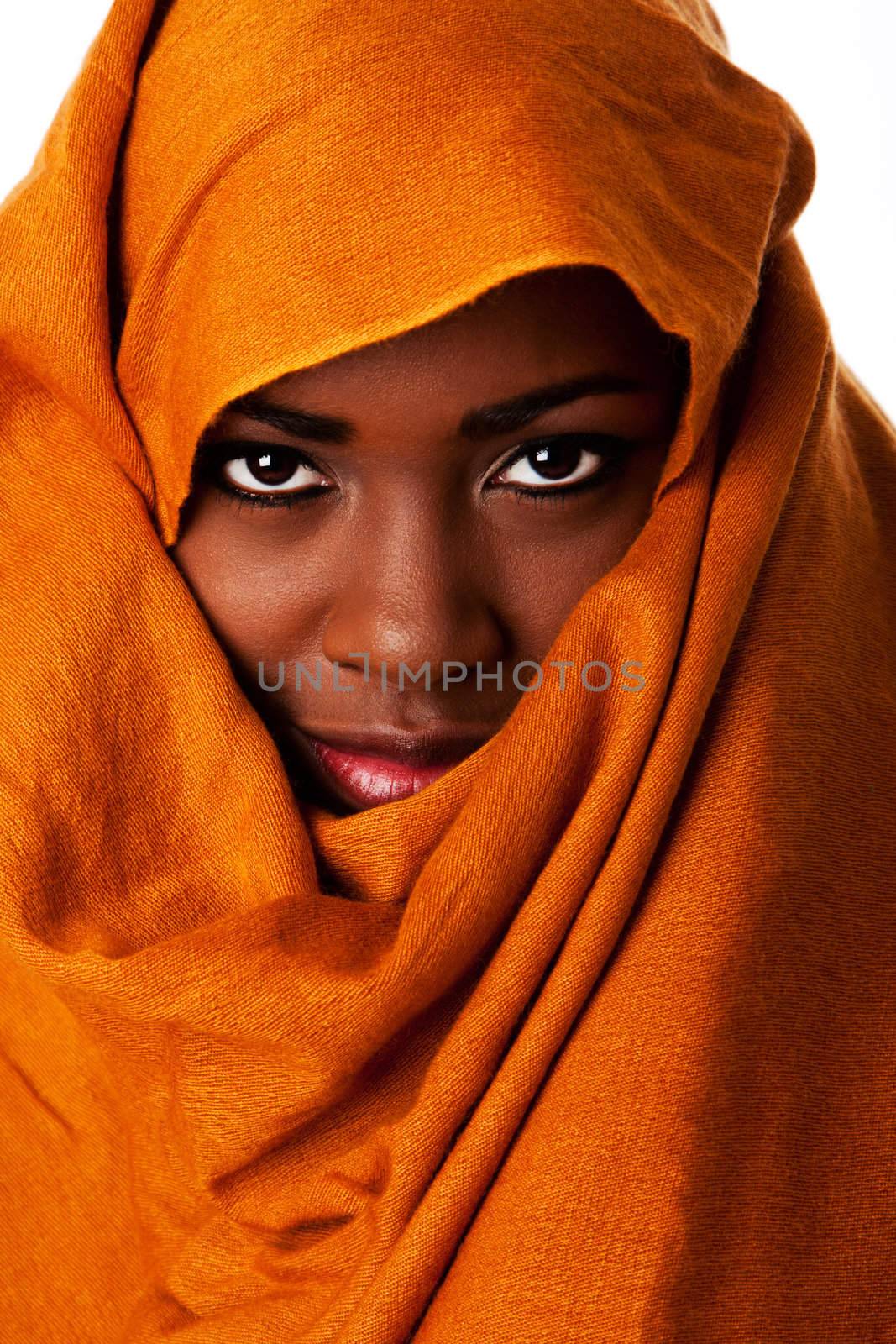 Beautiful mysterious african nomadic female face in ocher Earth tone head wrap scarf looking.