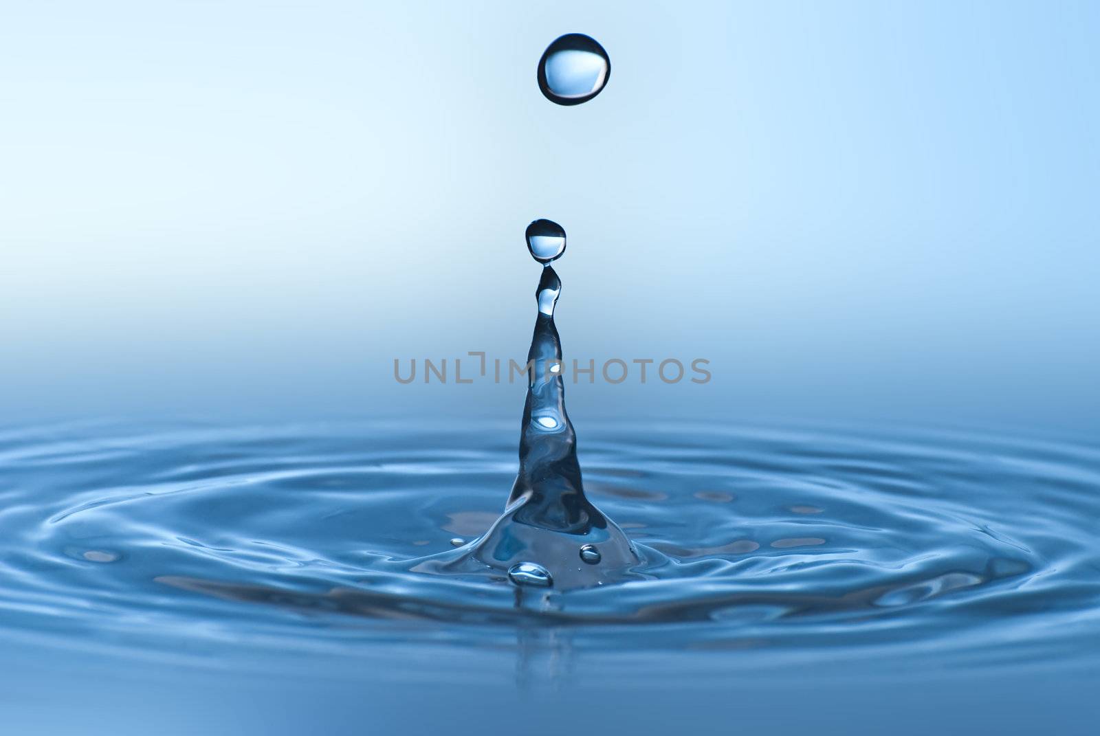 Clean blue drop of water splashing in clear water. Abstract blue environmental background.