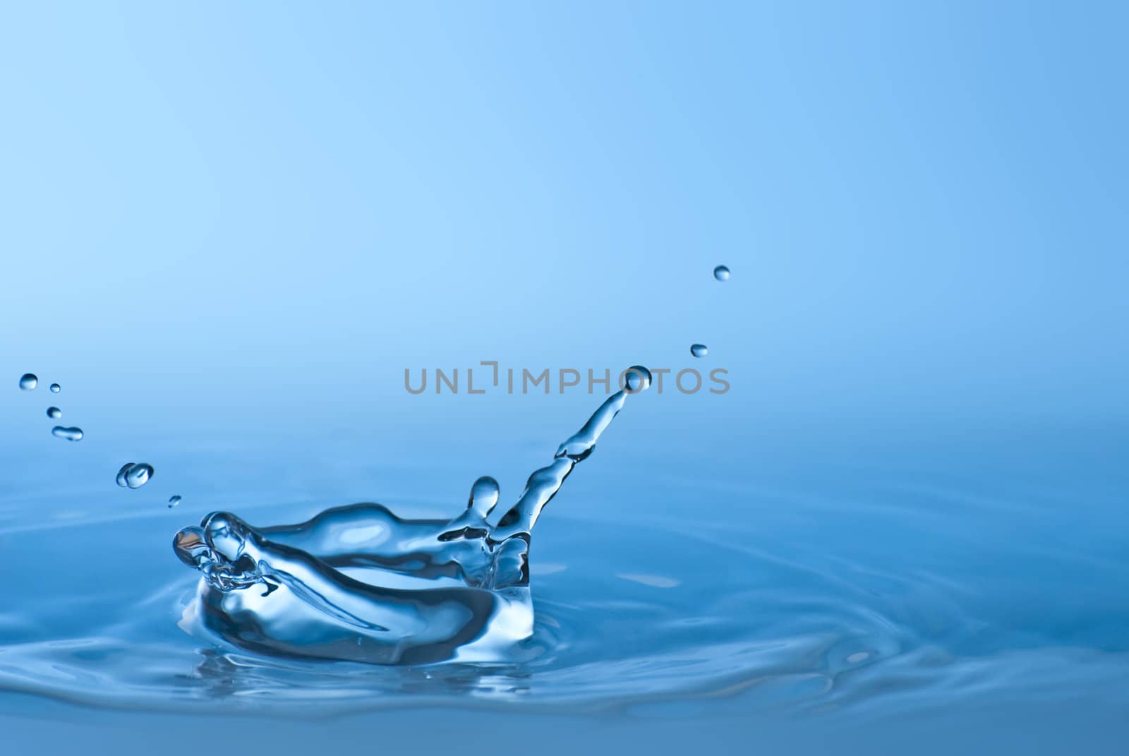 Clean blue drop of water splashing in clear water. Abstract blue environmental background.