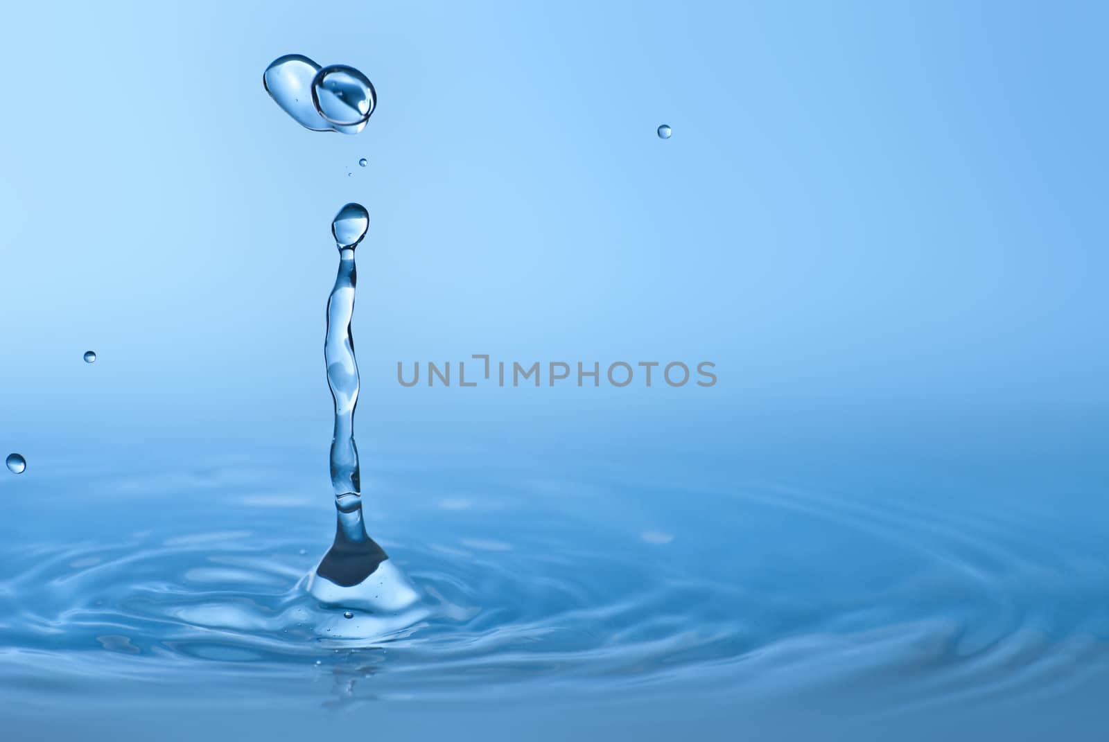 Clean blue drop of water splashing in clear water. Abstract blue environmental background.