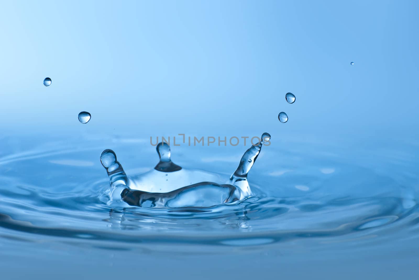 Clean blue drop of water splashing in clear water. Abstract blue environmental background.