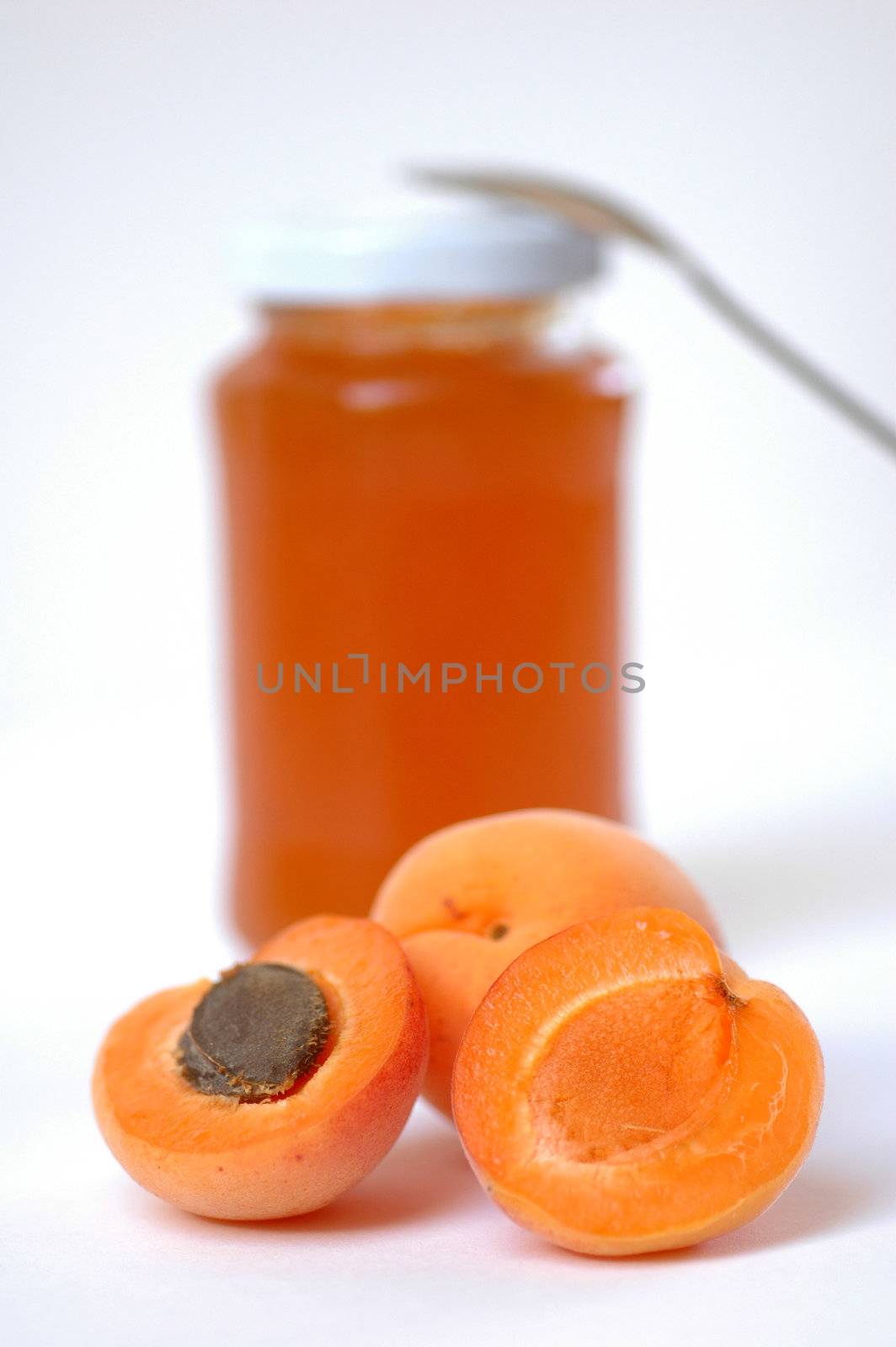 Apricot jam with two apricots in foreground