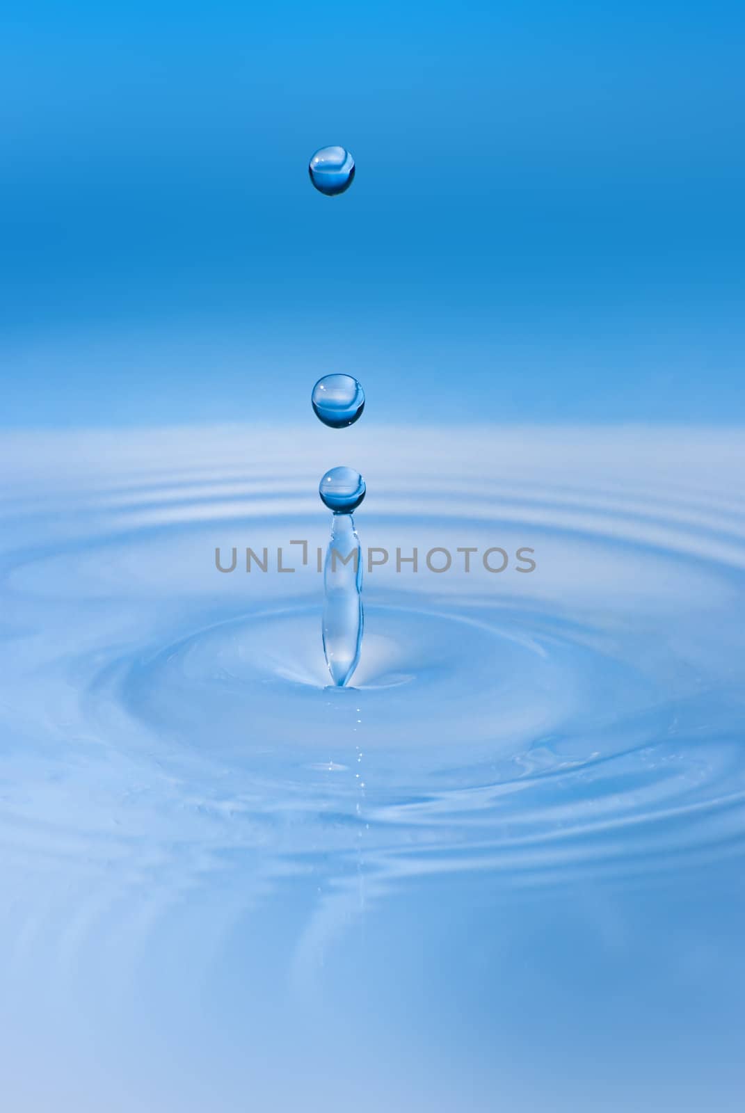 Clean blue drop of water splashing in clear water. Abstract blue by mozzyb