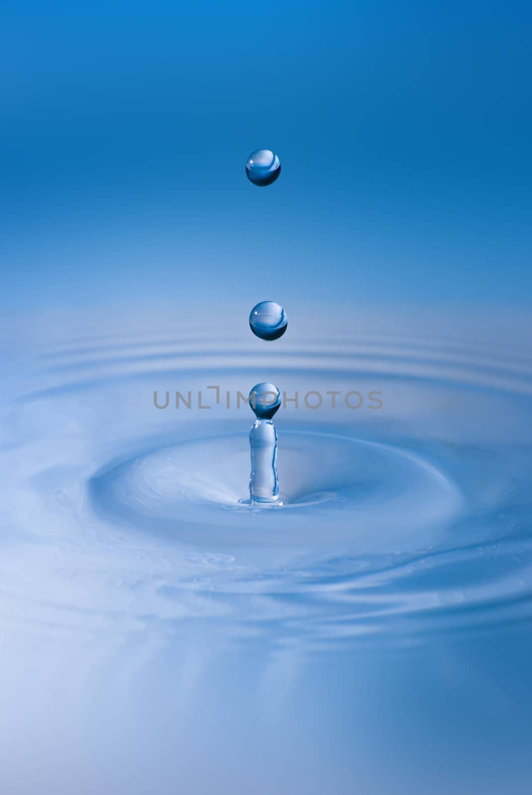 Clean blue drop of water splashing in clear water. Abstract blue environmental background.