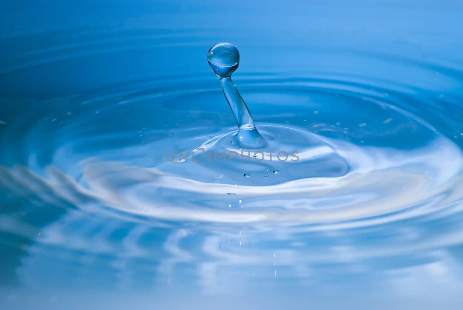 Clean blue drop of water splashing in clear water. Abstract blue by mozzyb