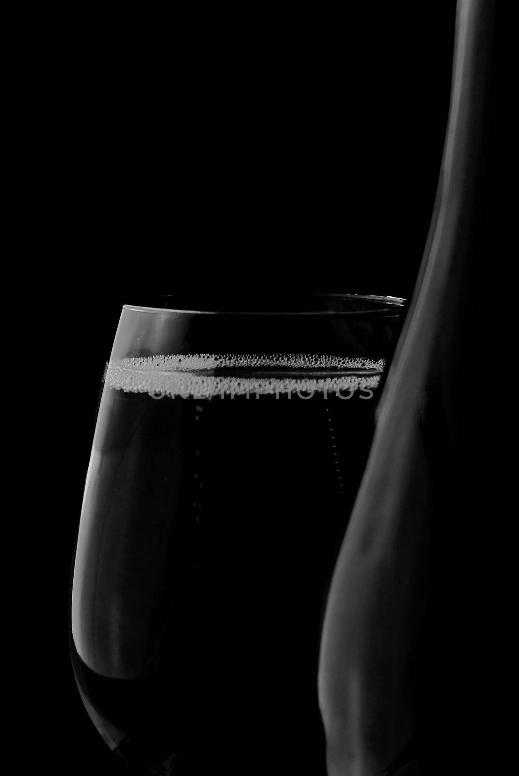 Merry Christmas and happy New year. Champagne glass and bottle isolated on black background.