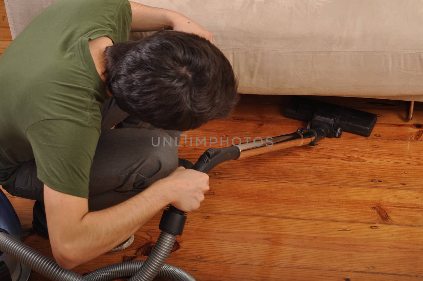 back view of a young man with vacuum cleaner doing the housework