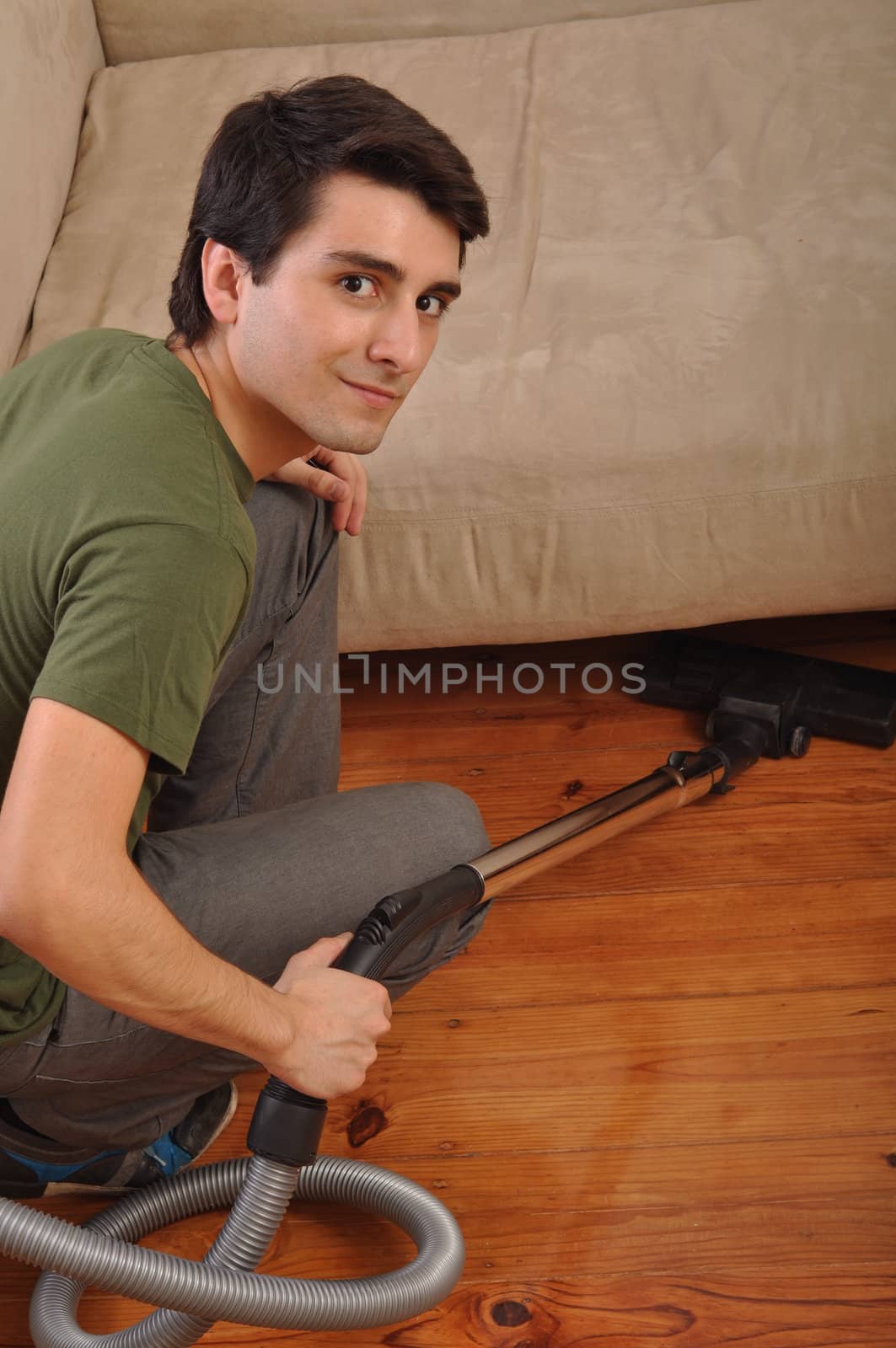 smiling young man with vacuum cleaner doing the housework